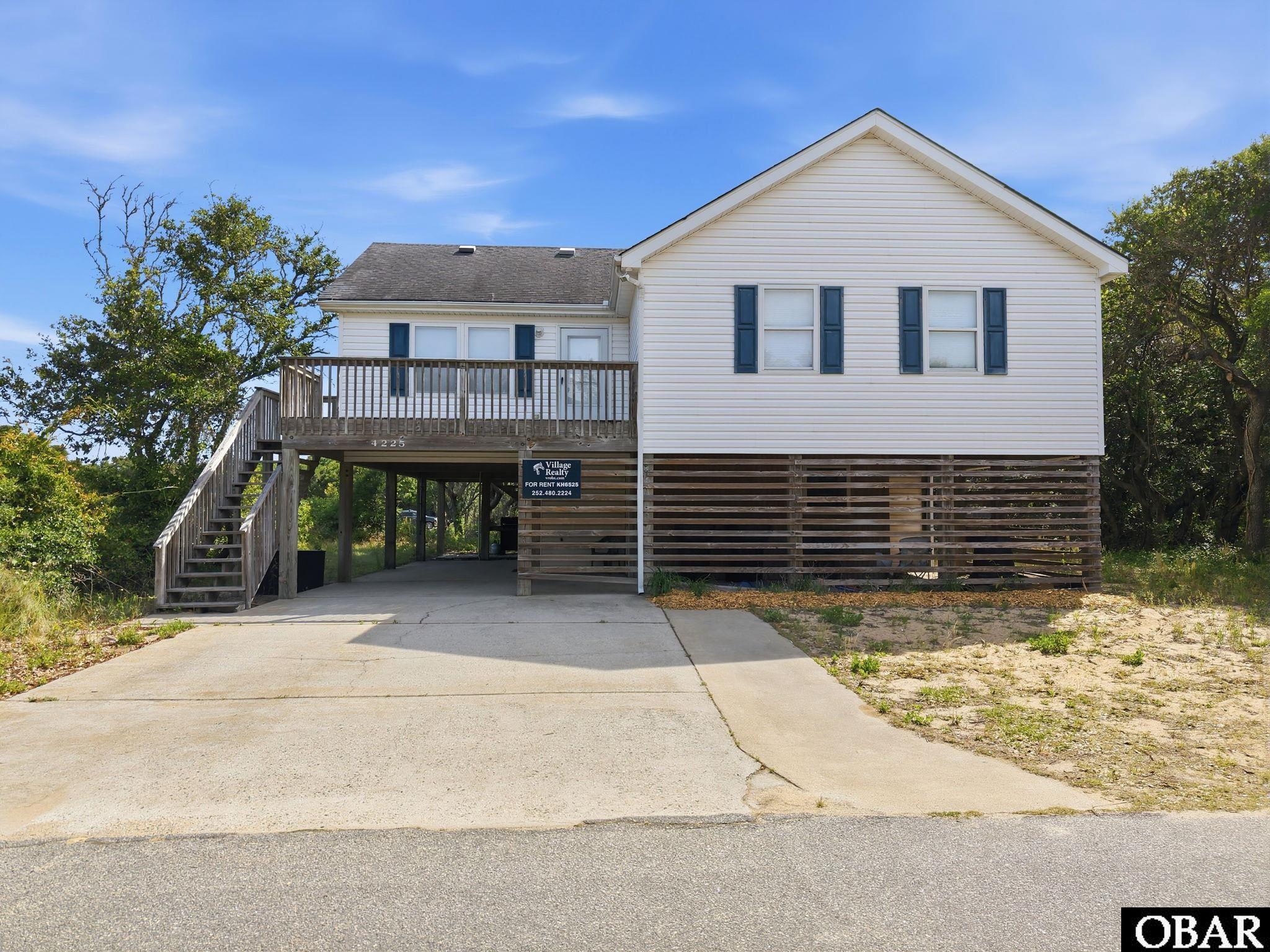 This coastal retreat offers the best of Outer Banks living with stunning golf course views from the front and less than one mile to multiple Kitty Hawk beach accesses. Nestled among a grove of beautiful live oaks and facing the Seascape Golf Course, this home provides the perfect blend of privacy, scenery, and convenience. This property combines comfort, style, and strong investment potential.  It's designed to comfortably accommodate 8–10 guests.  Tastefully decorated and furnished throughout, the upper level features 3 bedrooms with kind beds and 2 full baths, while the spacious ground-floor bonus room/bedroom features 2 bunk beds with fulls on the bottom, twins on top.  It offers exceptional flexibility with a connected full bath/laundry room, additional fridge & loveseat.  Between the covered parking under the house and the driveway, it easily fits 3–4 vehicles.  Recent updates include a 2023 Hot Tub, some new furniture, a new hot water heater, new washing machine.  Situated on a large homesite with plenty of room to add a pool and outdoor entertaining area, this property has endless possibilities. Whether you’re looking for a vacation rental, second home, or primary residence, this home truly has it all.