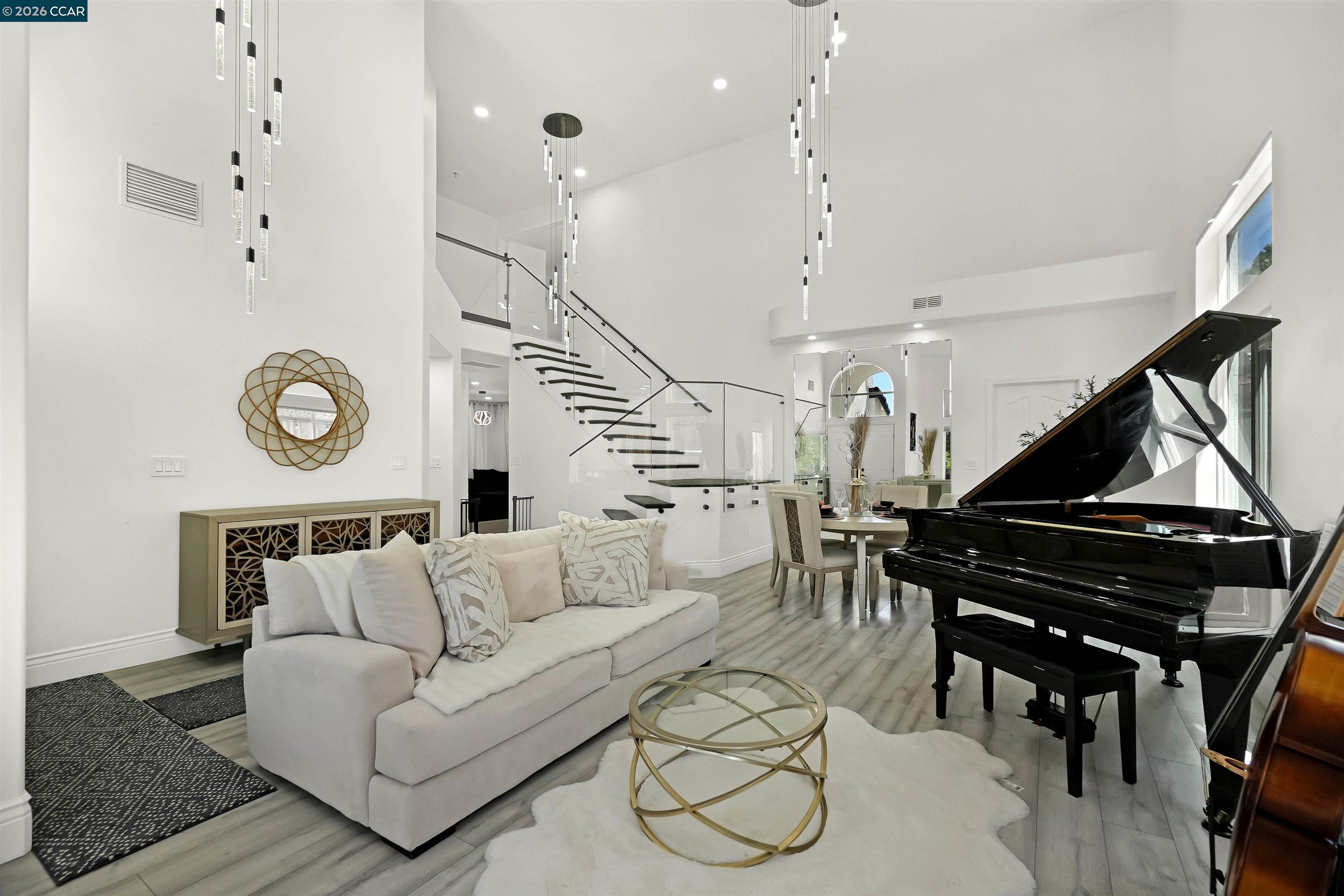Welcome to a home that makes an unforgettable first impression. Showcasing striking curb appeal, soaring ceilings, and a beautifully remodeled interior, this residence blends modern elegance with everyday comfort. Natural light pours into the impressive main living area, highlighted by a stunning fireplace, statement glass staircase, and upscale finishes throughout. The updated kitchen offers a clean, timeless design with sleek cabinetry, generous prep space, and seamless flow for both daily living and entertaining. Upstairs, the spacious primary suite feels like a true retreat, while the remodeled bathrooms and versatile bonus/media room add comfort and flexibility. Step outside to a thoughtfully redesigned backyard where towering trees create a striking natural backdrop and an added sense of privacy. Enhanced with a beautifully updated retaining wall, expansive concrete hardscape, and a spa, the outdoor space is both polished and functional. Ideal for entertaining, unwinding, and enjoying the setting year-round. Stylish, inviting, and thoughtfully upgraded, this is the kind of home that truly stands apart.