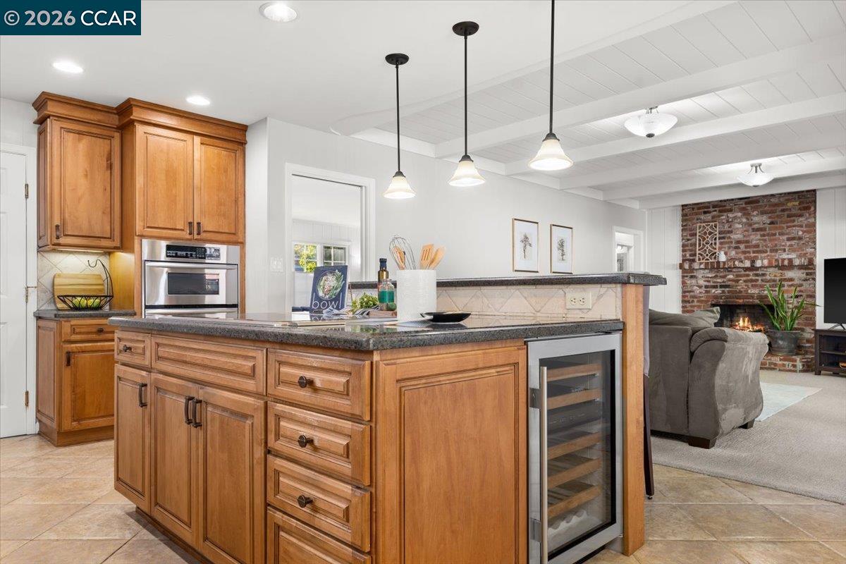 Set on a court in Vallejo's established Minahan Meadow neighborhood, this thoughtfully updated mid-century home welcomes you with instant curb appeal, then draws you in further with an effortless floor plan built for hosting - the kind of space that turns a weeknight dinner into a gathering and a weekend into a full-blown celebration. Wood paneling connects two distinct living spaces, each designed with its own purpose in mind. Up front, a bright, light-filled living room is ideal as a formal sitting room, home office, or media space. In back, a family room made for entertaining pairs a brick fireplace and vaulted wood beam ceiling with windows and a sliding glass door that frame the backyard just beyond, keeping the party going right out the door. At the center of it all, a kitchen made for the home chef in you brings a Wolf electric cooktop set into the island, beveled granite counters, a breakfast bar, double ovens ready for holiday feasts, and a wine fridge to keep the toasts coming. A glass door and window off the adjoining dining nook bring in extra light, opening onto a spacious patio and garden complete with a covered wood trellis for grilling under string lights, all framed by a charming white picket fence. The primary bedroom offers a walk-in closet with wood organizers and its own vanity area, with a dedicated, boutique-hotel-style bath just steps away, while the original hall bath retains a modern vintage flair, full of character and ready for your personal touch. Each of the three bedrooms is finished with the same wood-paneled walls and its own painted accent wall, while the secondary bedrooms also feature new LED lighting and matching wood-organized closets. Central heat and air keep the home comfortable in every season, and a two-car garage with built-in storage means there's room for everything, from holiday decor to backyard gear, right where you need it. Centrally located in the North Bay, Vallejo puts Napa wine country within easy reach, while the Vallejo Ferry Terminal, just 3 miles away, offers a scenic alternative to bridge traffic into San Francisco. Enjoy Vallejo's waterfront charm, historic and up-and-coming downtown, and all that this special property has to offer.