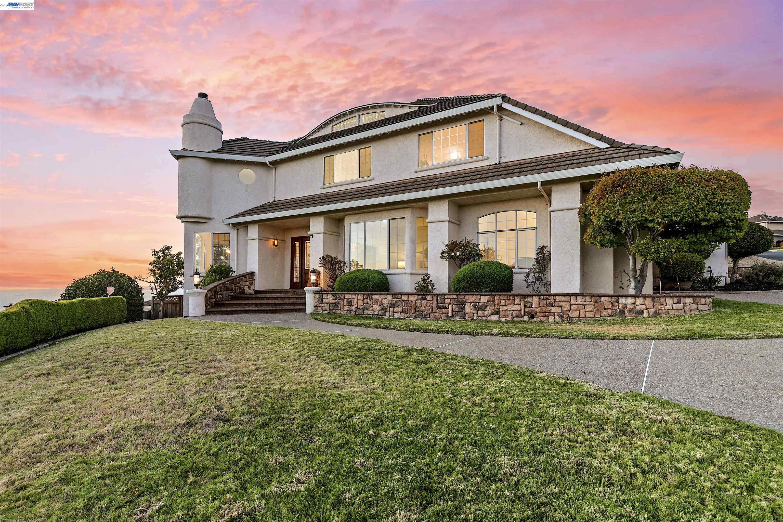 Perched majestically on a premier Fairview hilltop, this Ridgeview Terrace custom estate combines grand architectural design with ultimate privacy. Standalone with no side neighbors, the property features a stately facade and a spacious four-car garage. Enjoy clean hillside breezes and an uncompromised 180-degree view of the Bay, the iconic Bay Bridge, and glittering city lights. The current owners fell in love with this exact view over 30 years ago, convincing the community’s builder—who had crafted this masterpiece for themselves—to sell it to them. Freshly painted main level features beautiful new LVP flooring, a formal dining area, and a refreshed kitchen with a new gas cooktop, double oven, stainless steel appliances pantry and breakfast bar. Directly adjacent to the kitchen is the family room, where built-in shelves and a focal fireplace anchor the space. All common areas are surrounded by windows to maximize views and the elegant French doors create a flawless indoor-outdoor flow to the paved backyard. The main floor transitions smoothly into the adjoining living room and a den perfect for a home office—and hosts a downstairs bedroom ideal for guests or extended family. Upper level offers new carpet, a bonus room with adjacent storage highlighted by a beautiful stained-glass motif dome in the hallway. The primary suite features a refreshed vanity area with spectacular views and a walk-in closet, while two well-appointed secondary bedrooms share a spacious hall bath. This hidden gem offers a peaceful lifestyle minutes from outdoor recreation at Don Castro, with a swift commute via I-580 and BART. Celebrating wonderful memories from the past 30 years, this lovely home awaits its next chapter. Sale includes two parcels (APN: 425-210-19 11,208 sq ft and 425-210-20 2,887 sq ft) for a combined 14,095 sq ft lot.