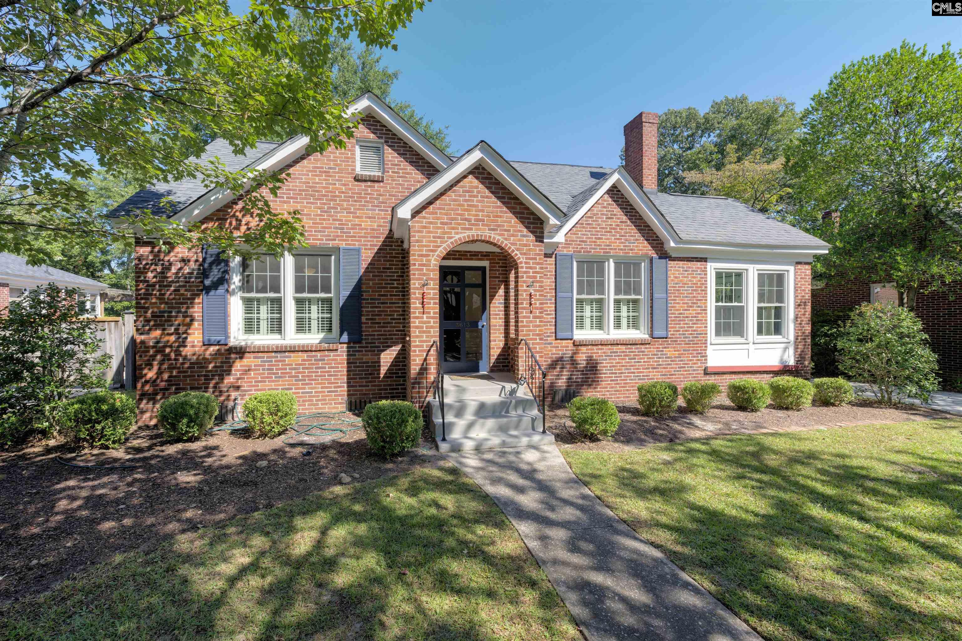 Red-brick house with an arched entry, blue shutters, and a front lawn.