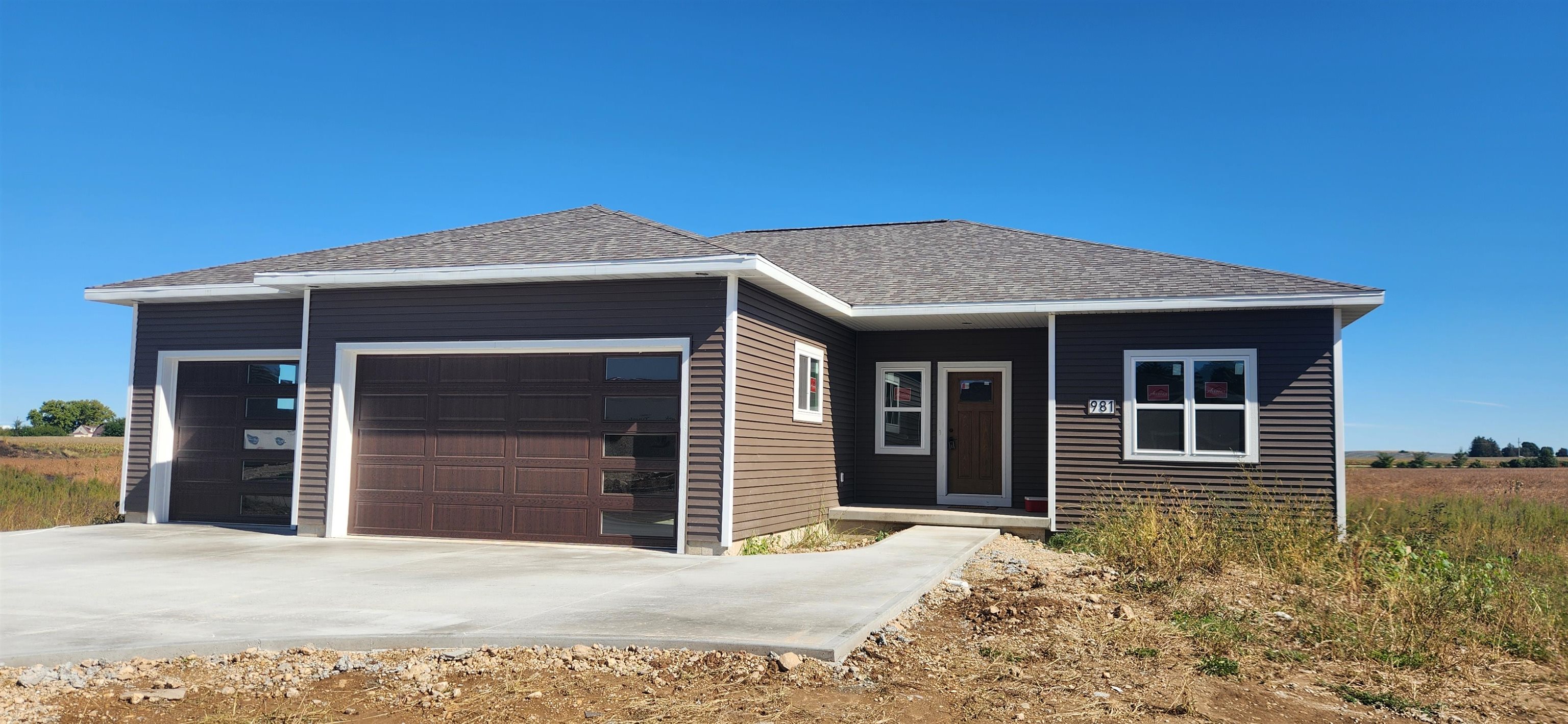 Single-story dark-sided home with a two-car garage and unfinished landscaping.