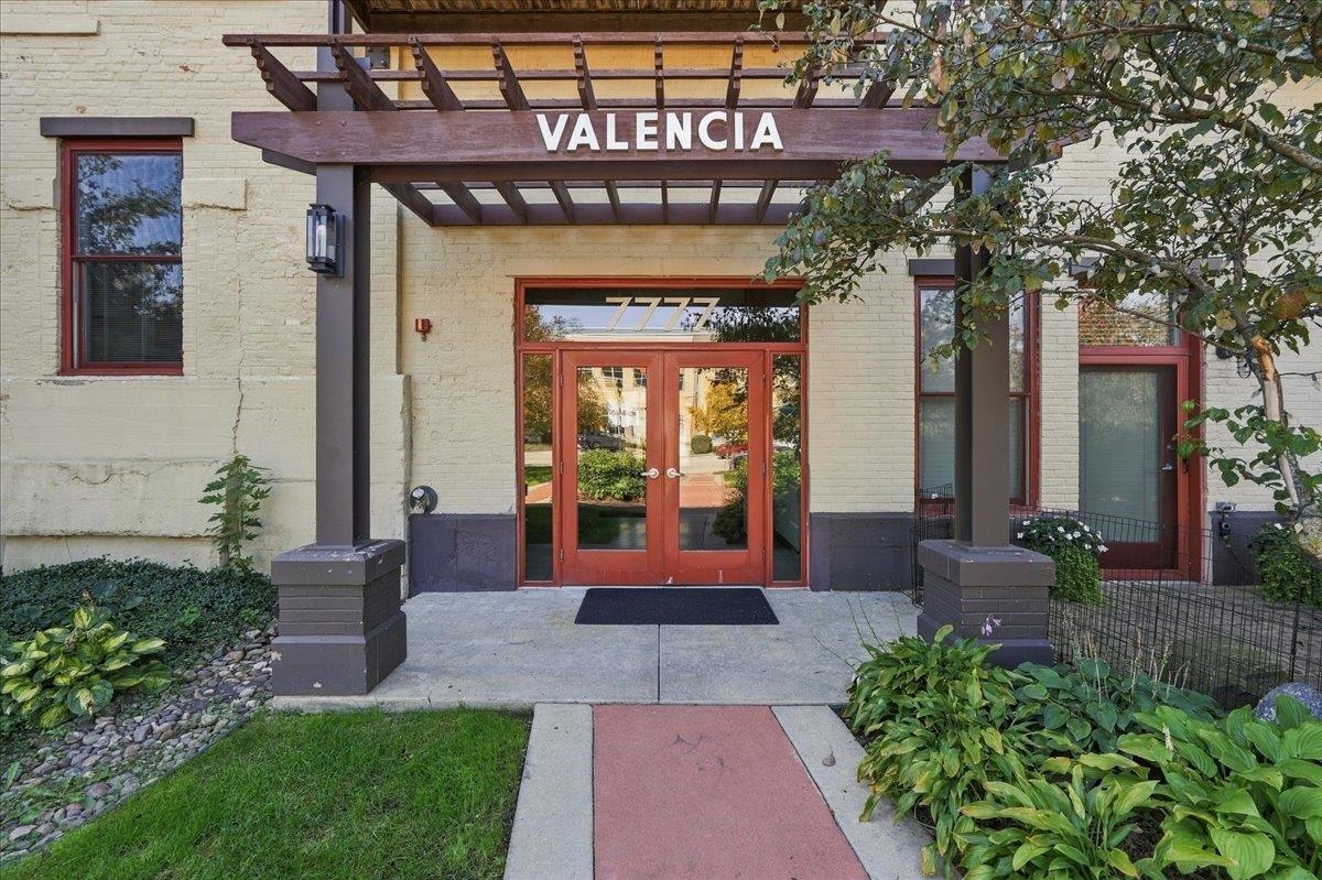 Valencia building entrance with a wooden pergola and red-framed double doors.