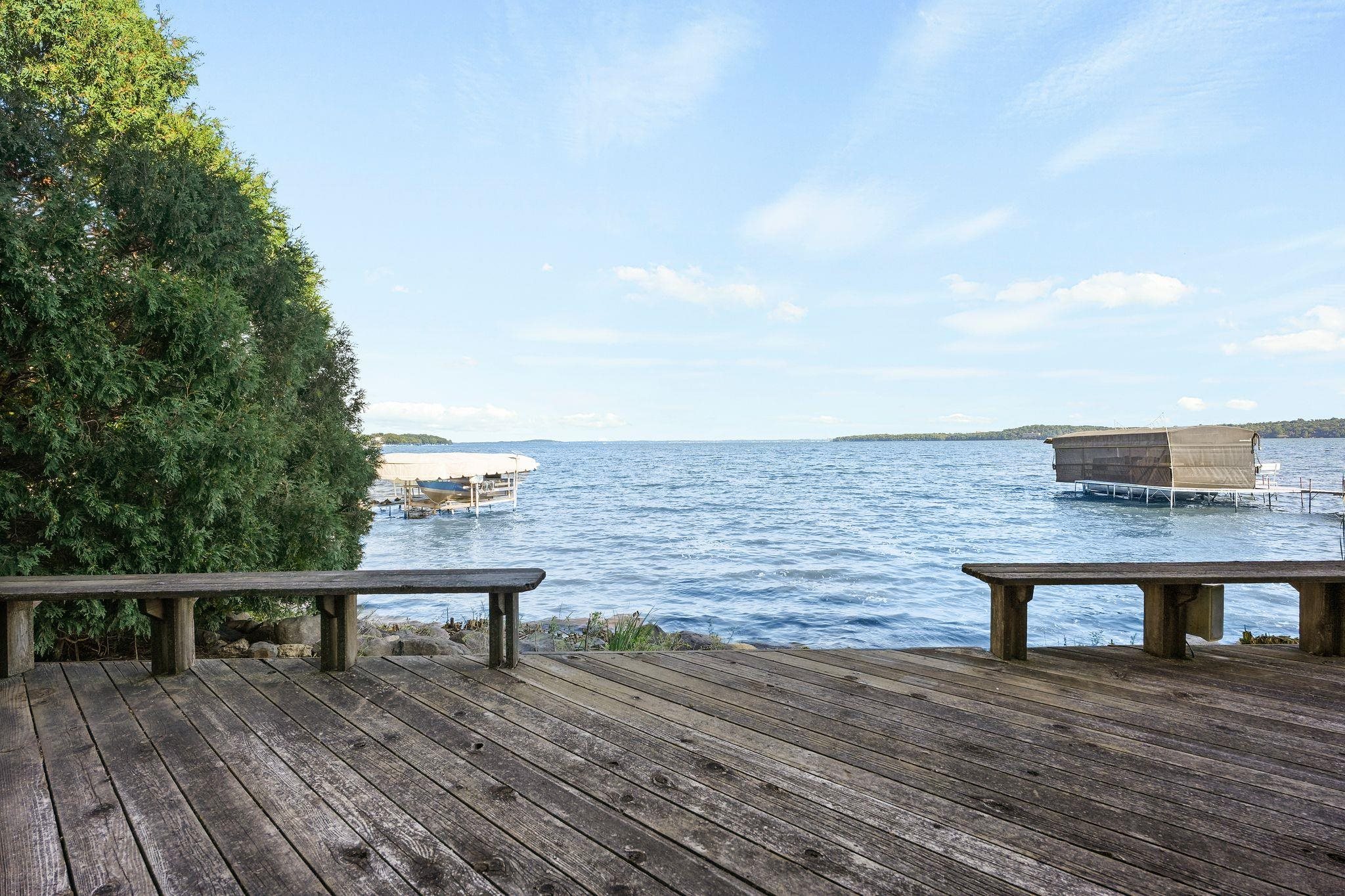 Rare opportunity to enjoy lake living from an exceptional setting at the end of a quiet dead-end street with 45 feet of lake frontage and some of the area's most impressive long-water views, including beautiful sunrises and moonrises over the lake. This well-maintained home currently offers two bedrooms, highlighted by a remarkable primary suite that occupies the entire second floor and creates a spacious, private retreat. The floor plan also offers a straightforward and relatively inexpensive opportunity to add a third bedroom with minimal impact to the existing living spaces. The location is equally special, with easy access to the 600+ acre Pheasant Branch Conservancy, Harbor Athletic Club, restaurants, Starbucks and more, all while coming home to an unusually private waterfront setting with exceptional end-to-end lake views.