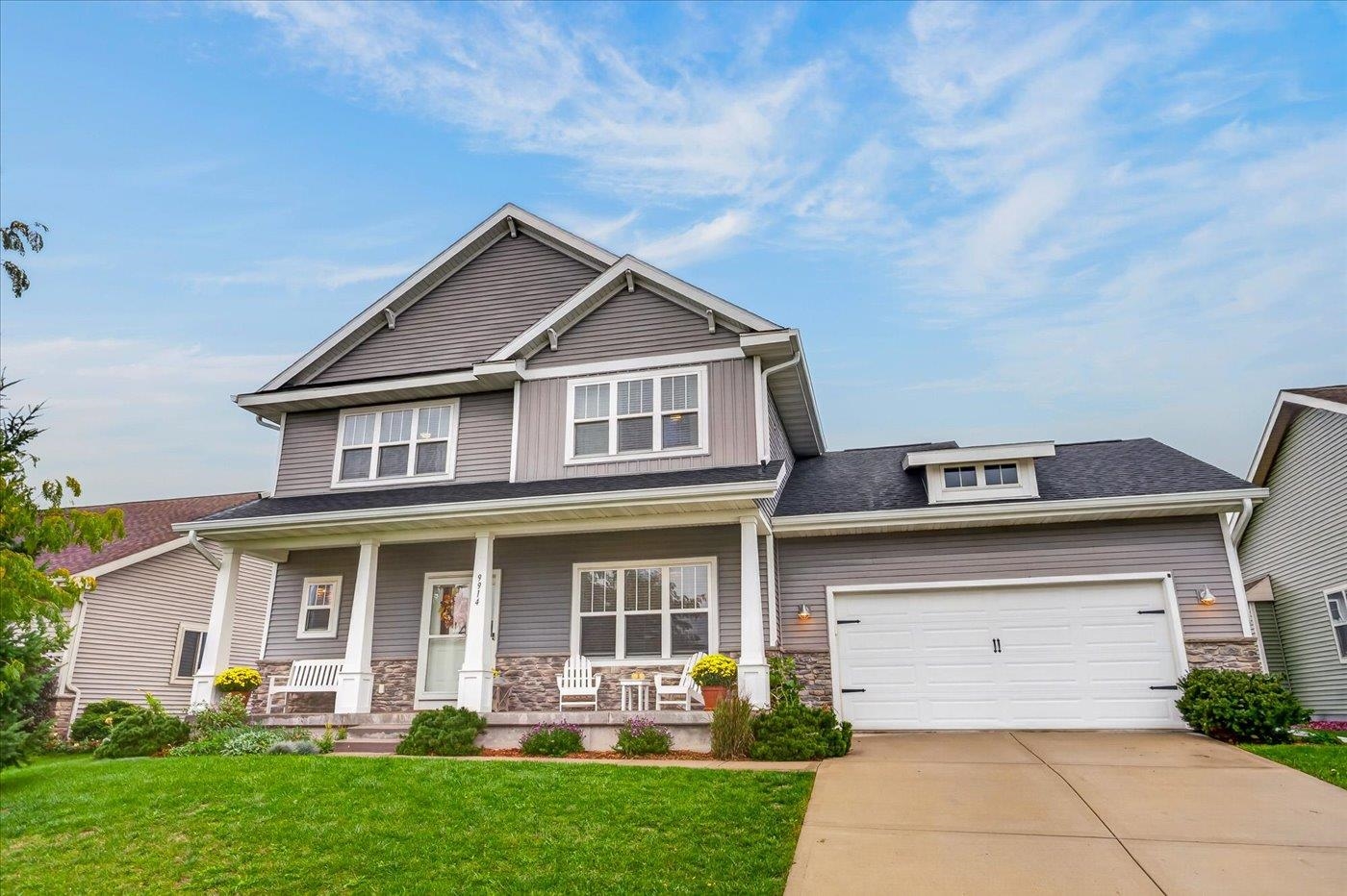 Gray two-story house with a covered porch, stone accents, and attached two-car garage.