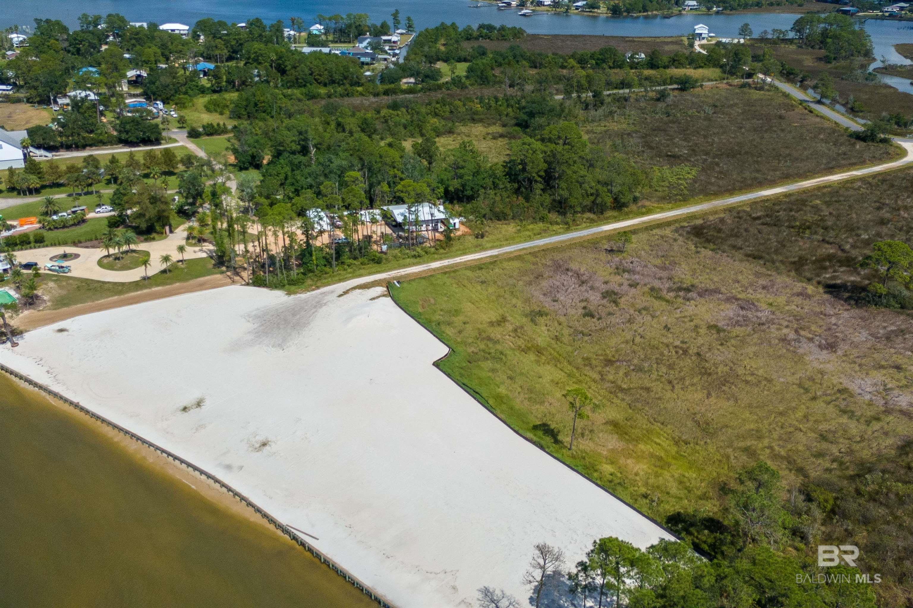 VERY Rare 425 Waterfront Development Opportunity in the Heart of Gulf Shores!  An exceptionally rare opportunity to acquire 425 feet of direct waterfront frontage with unobstructed views of Mobile Bay and Bon Secour Bay. This prime waterfront tract has been approved with plans for 11 land-condominium single-family residences, a community pool, and a large pier featuring 12 boat slips—an extraordinary offering in today’s market.  The property is un-zoned, allowing flexibility for alternative development opportunities, including condominium, restaurant or other residential concepts (buyer to verify). Utilities are already approved and installed to the end of the drive, including water, sewer, overhead power, and security lighting. Infrastructure improvements include approximately 940 feet of water main, 940 feet of sewer force main, overhead power, and a rock road base prepared for future asphalt if desired.  This waterfront site boasts 425 feet of bulkhead installed along the waterfront providing continuous direct waterfront views. The property features beautiful white sandy uplands, ready for construction. Lot sizes range from approximately 28' x 60' to 30' x 60', with planned unit sizes ranging from 1,500 to 1,920 square feet per story, with the option to build up to three or more stories.  Enjoy minutes-by-boat access to the Gulf of Mexico, making this an ideal location for boating enthusiasts and coastal living. Situated in the heart of Gulf Shores, the property is conveniently close to renowned attractions, dining, and entertainment. Buyer to verify all information during due diligence.
