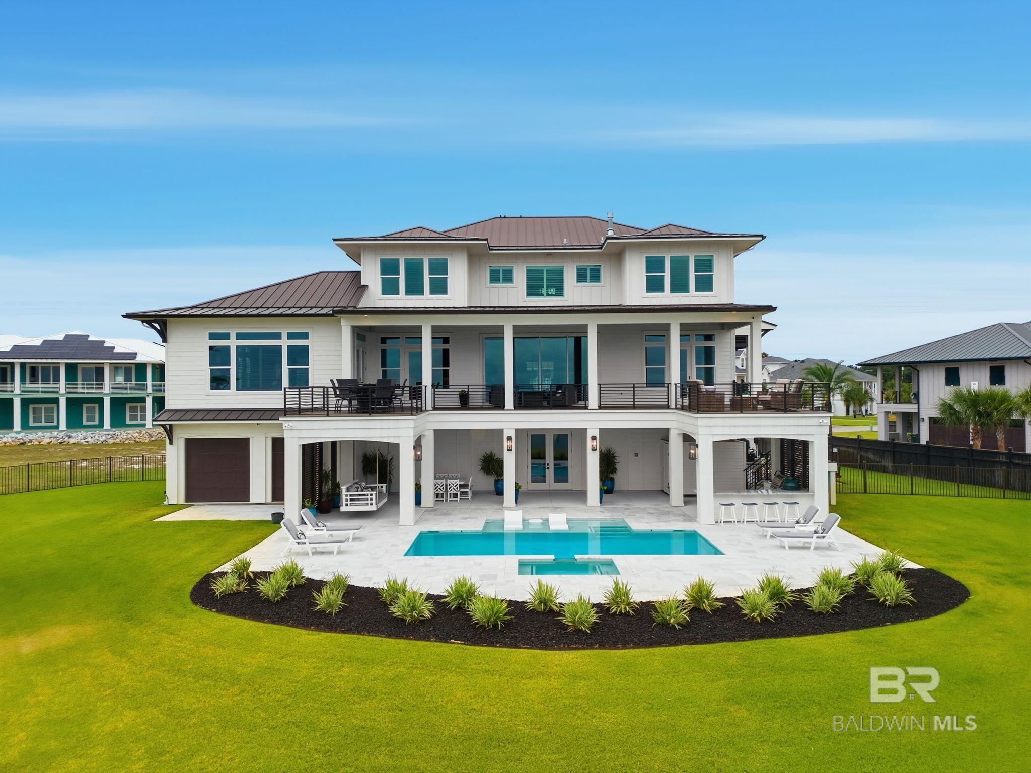 Experience luxury coastal living at its finest in this breathtaking 5-bedroom, 5 bath estate perfectly positioned on a ½-acre cul-de-sac lot with 217 feet of pristine waterfront on the Intracoastal Waterway and a private boat basin. Enjoy panoramic views of the Intracoastal and the Gulf, where gorgeous sunrises and stunning sunsets fill the sky each day—and watch the Blue Angels fly from the comfort of your own backyard. A boater’s paradise, this property offers direct access to the Intracoastal Waterway and is in close proximity to the Pass, providing effortless access to the Gulf of America or fishing, cruising, and coastal adventures. Inside, the home showcases white oak hardwood floors throughout, beautiful moldings, luxury marble and tile bathrooms, and a gourmet kitchen adorned with quartz countertops and backsplash, black stainless designer appliances, a Wolf built-in coffee system, and a butler’s pantry featuring custom cabinetry and walnut counters. The Bar & Game Room exudes a stylish speakeasy vibe, featuring a gas fireplace, walnut bar, beverage refrigerator, Scotsman ice maker, and beverage dispenser—a perfect gathering place for friends and family. Step outdoors to your private resort-style retreat with a Gunite heated pool and spa, surrounded by marble decking, and an outdoor kitchen equipped with a Blaze gas grill, Large Green Egg, beverage fridge, prep sink, and a full outdoor bathroom for added convenience. Additional highlights include a whole-house gas generator, an elevator servicing all three floors, and en-suite bedrooms finished with quartz, marble, and designer tile. Celebrated for its exceptional design and craftsmanship, this home has been featured in multiple luxury coastal magazines—a true testament to its architectural distinction and timeless beauty. This extraordinary waterfront residence seamlessly blends modern sophistication, comfort, and the ultimate coastal lifestyle.   Buyer to verify all information during due diligence.