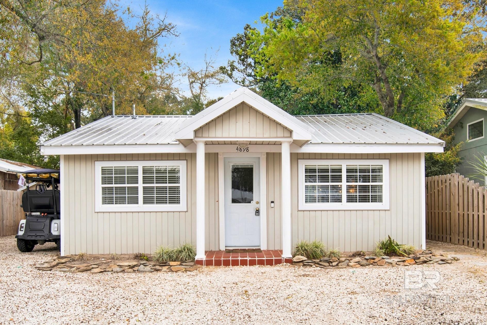 Welcome to this beautifully updated cottage located in the heart of Orange Beach. This inviting home offers a comfortable open layout with a seamless flow between the living room, dining area, and kitchen, creating a space that works well for everyday living as well as hosting guests. The kitchen features stainless steel appliances, quartz countertops, and plenty of cabinet space, giving it a clean, modern feel while remaining practical and functional. The home includes three bedrooms and three bathrooms, providing ample space for occupants and guests. Several important updates have already been completed, including a FORTIFIED roof and an HVAC system installed in 2021, offering added durability, efficiency, and peace of mind for the next owner. Step outside to the large, fenced backyard, offering plenty of space for outdoor gatherings, hobbies, or simply enjoying time outside. The property also features a detached storage shed with electricity and plumbing already in place, creating a flexible space that could be used as a workshop, studio, or additional storage area. In front of the home, there is a spacious parking area along with a convenient EV charging outlet. Residents of the neighborhood enjoy access to a community boat dock that allows kayaks and paddleboards, making it easy to get out on the water and enjoy the coastal lifestyle. The property also offers the benefit of NO HOA and flood insurance is not required, helping reduce ongoing ownership costs. Location is one of the highlights of this home, conveniently situated close to the beach, local schools, the library, and the arts center. Buyer to verify all information during due diligence.