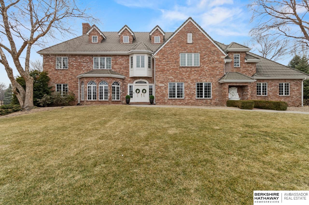 Located on the 6th green of Shadow Ridge Golf Course in The Ridges, this one of a kind all brick two story home showcases distinctive architectural elements sourced from notable historic Omaha buildings, including fireplace marble from the former Federal Reserve Building, a staircase from the historic Medical Arts Building, and limestone doorways, windows, and wood details from the Storz Mansion dating back to the 1800s. The second level includes four bedrooms, highlighted by an oversized primary suite with walk in closet and marble tile bath. The third floor offers a versatile bonus space. The finished lower level is thoughtfully designed for entertaining with a recreation room, bar area, game space, wine cabinet, and hidden cabinetry. The kitchen features high end stainless steel appliances including a Sub Zero refrigerator. Additional highlights include a sunroom overlooking the golf course and a paver patio.