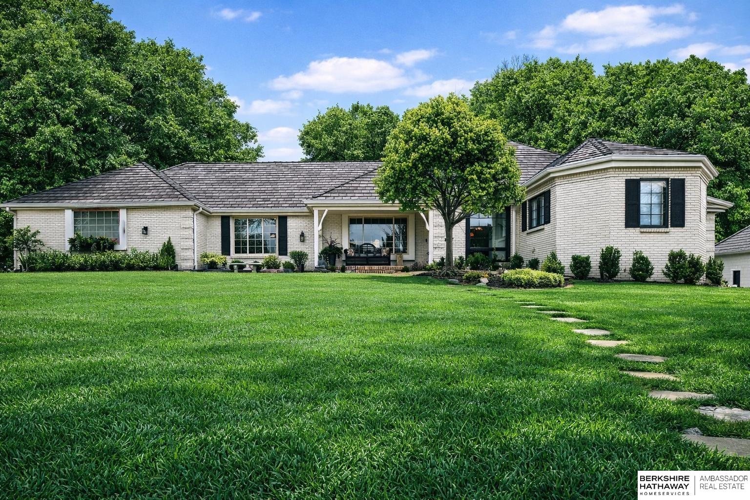 Welcome to a rare opportunity in Omaha’s coveted Regency neighborhood. This stately brick 1.5-story walkout ranch sits on a beautifully landscaped corner lot offering privacy and tranquility. Completely remodeled top to bottom from 2023–2025, the home features close to 5,300 finished sq ft with 5 bedrooms, 5 baths, and a 4-car garage. The reimagined main floor primary suite offers a spacious bedroom, spa-like bath, and large walk-in closet. Upstairs includes 3 generous bedrooms-one with ensuite and two with Jack-and-Jill bath-plus a cedar closet, third laundry, and added storage. The stunning kitchen boasts all-new cabinetry, appliances, countertops, flooring, and lighting. Main-floor office, backyard access  & two laundry spaces add convenience. Finished lower level includes a large rec room, bedroom, workout room, wet bar, and storage. DaVinci roof (2016). Enjoy HOA pool, tennis courts, and clubhouse in one of Omaha’s most desirable communities. Exterior photos are summer renderings.