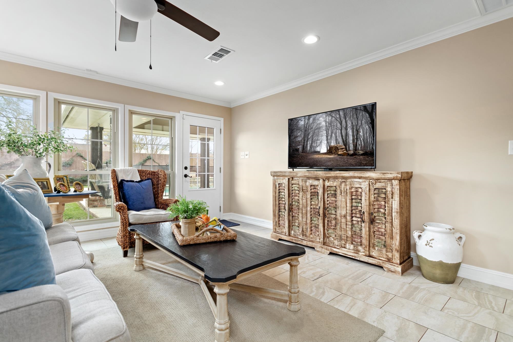 Living room seating area with wicker chair, coffee table, and rustic media console