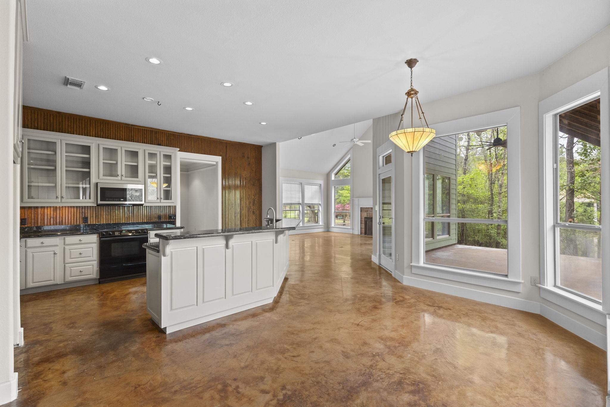 Open kitchen and dining area with wood backsplash, white cabinets, and access to outdoor deck