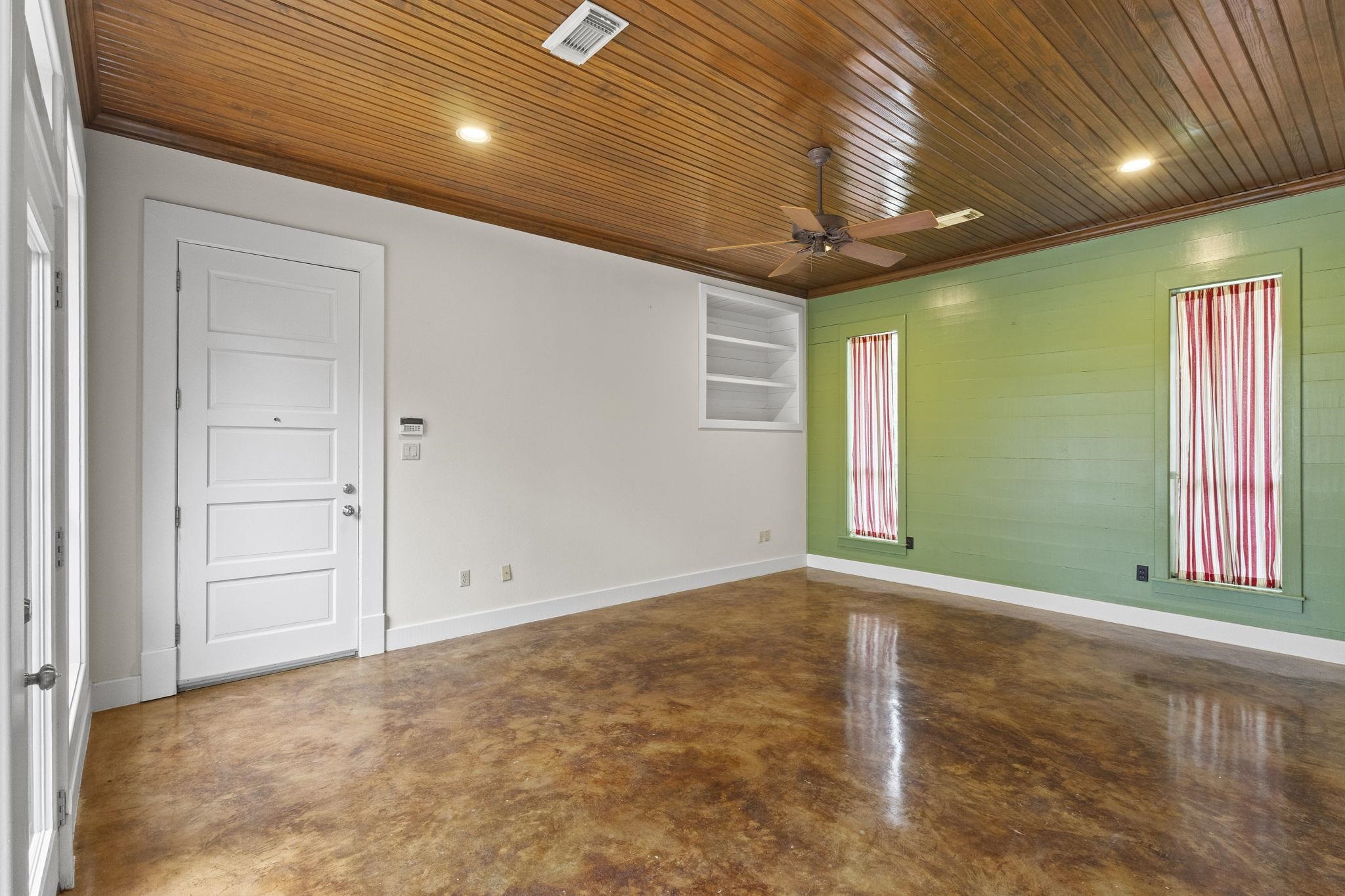 Family room with wood plank ceiling, green accent wall, and polished concrete floors