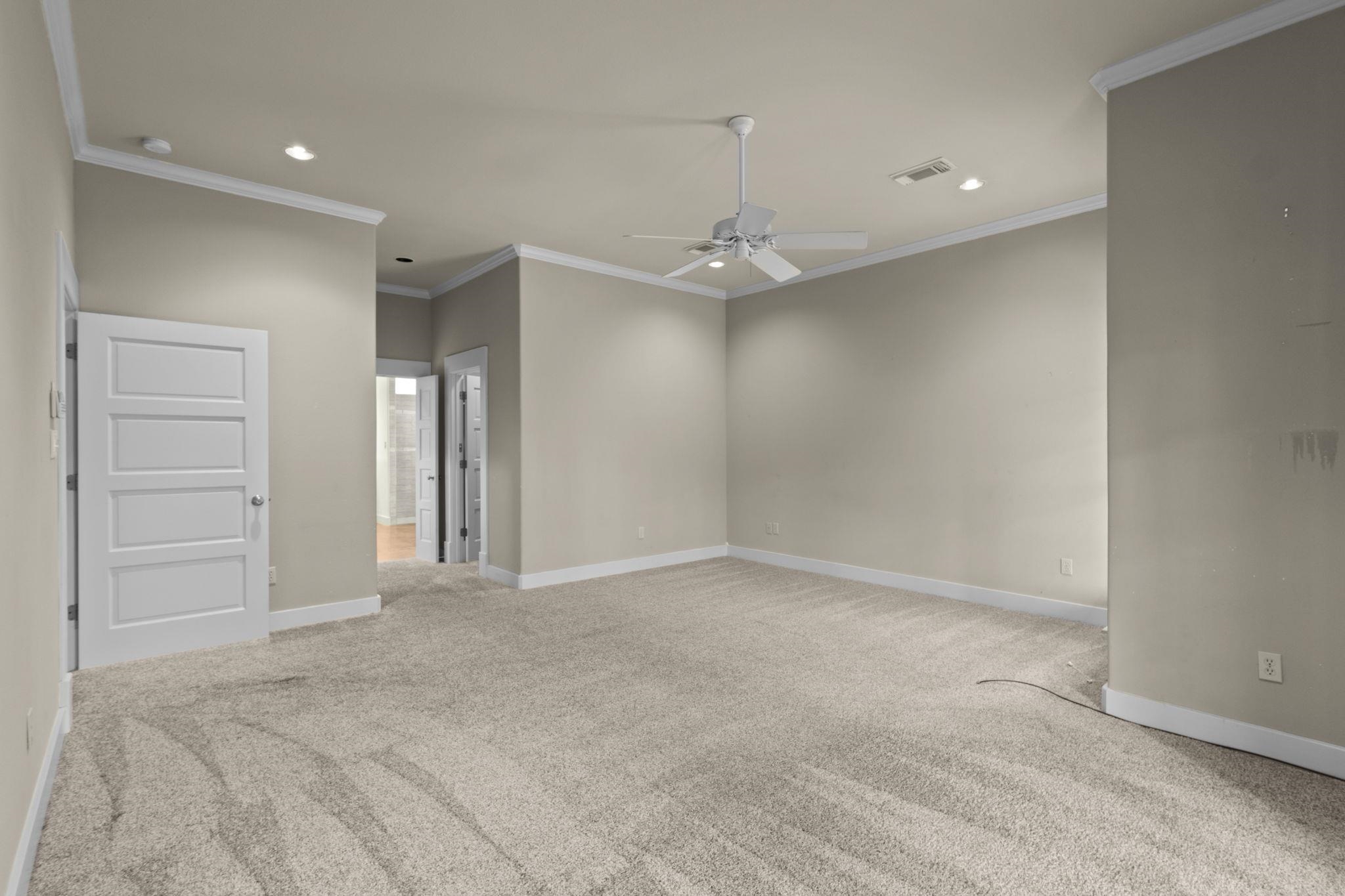 Secondary bedroom with neutral carpet, ceiling fan, crown molding, and white five-panel door