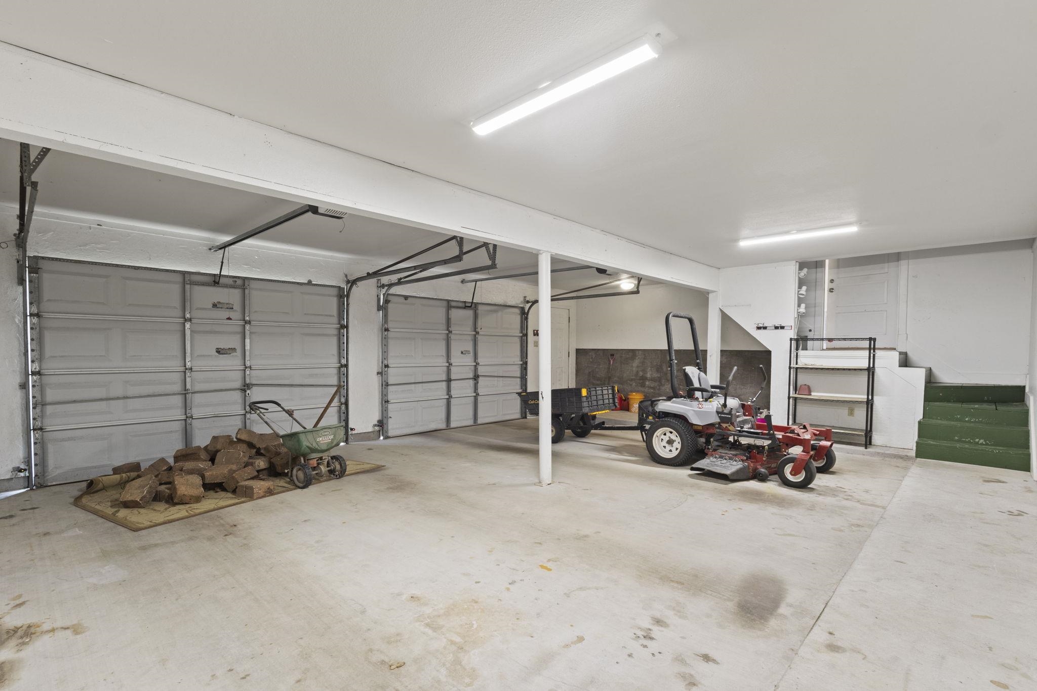 Three-car garage with concrete floors, exposed beams, and storage space