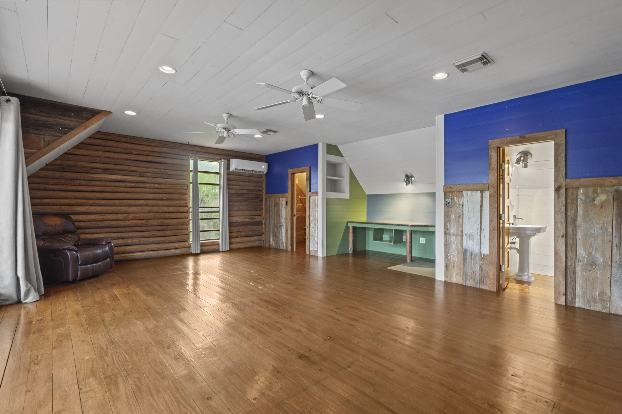 Recreation room showing built-in entertainment center with colorful accent walls and rustic wood paneling