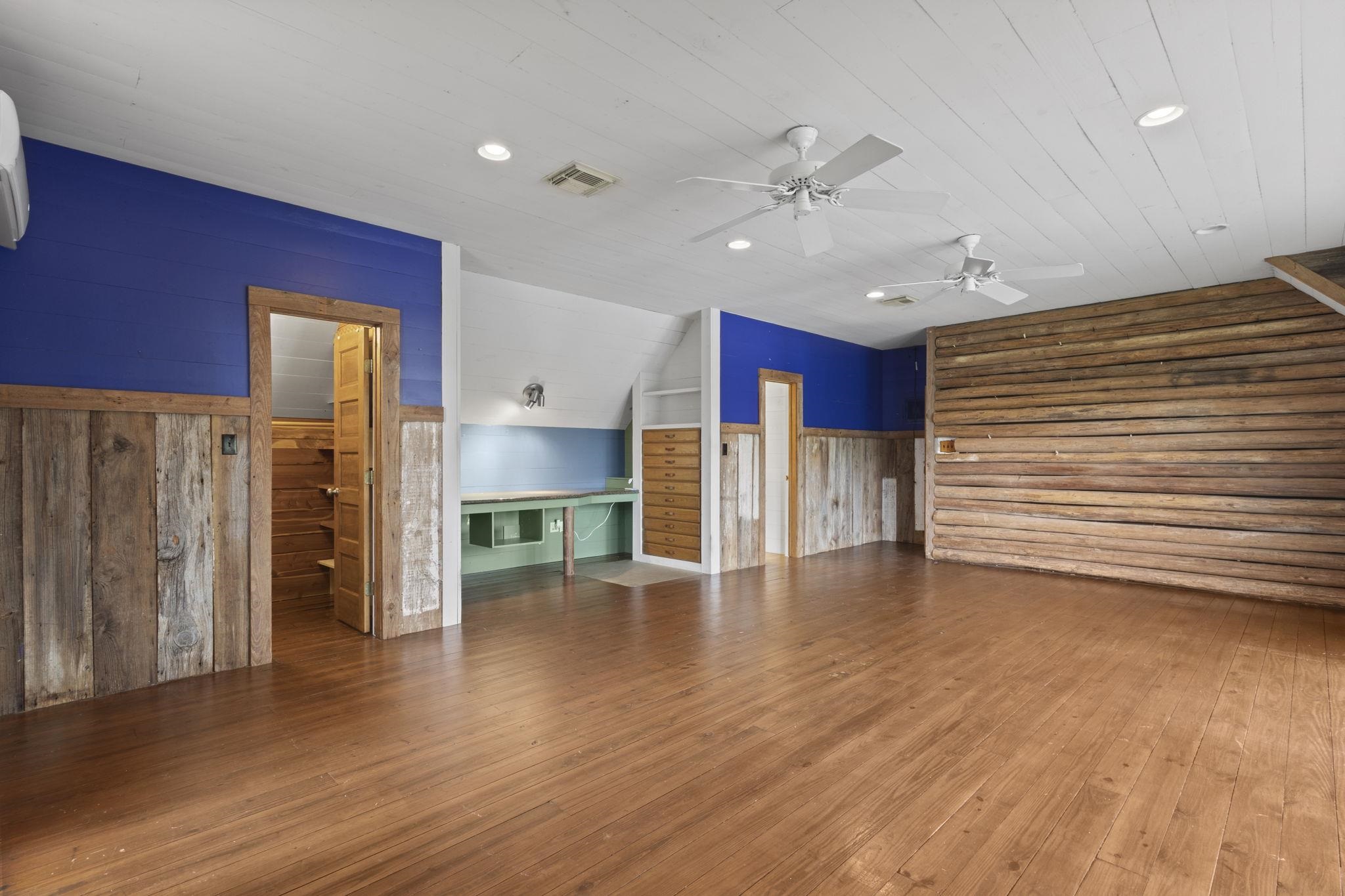 Game room with blue accent wall, built-in storage, and mix of rustic wood and modern finishes