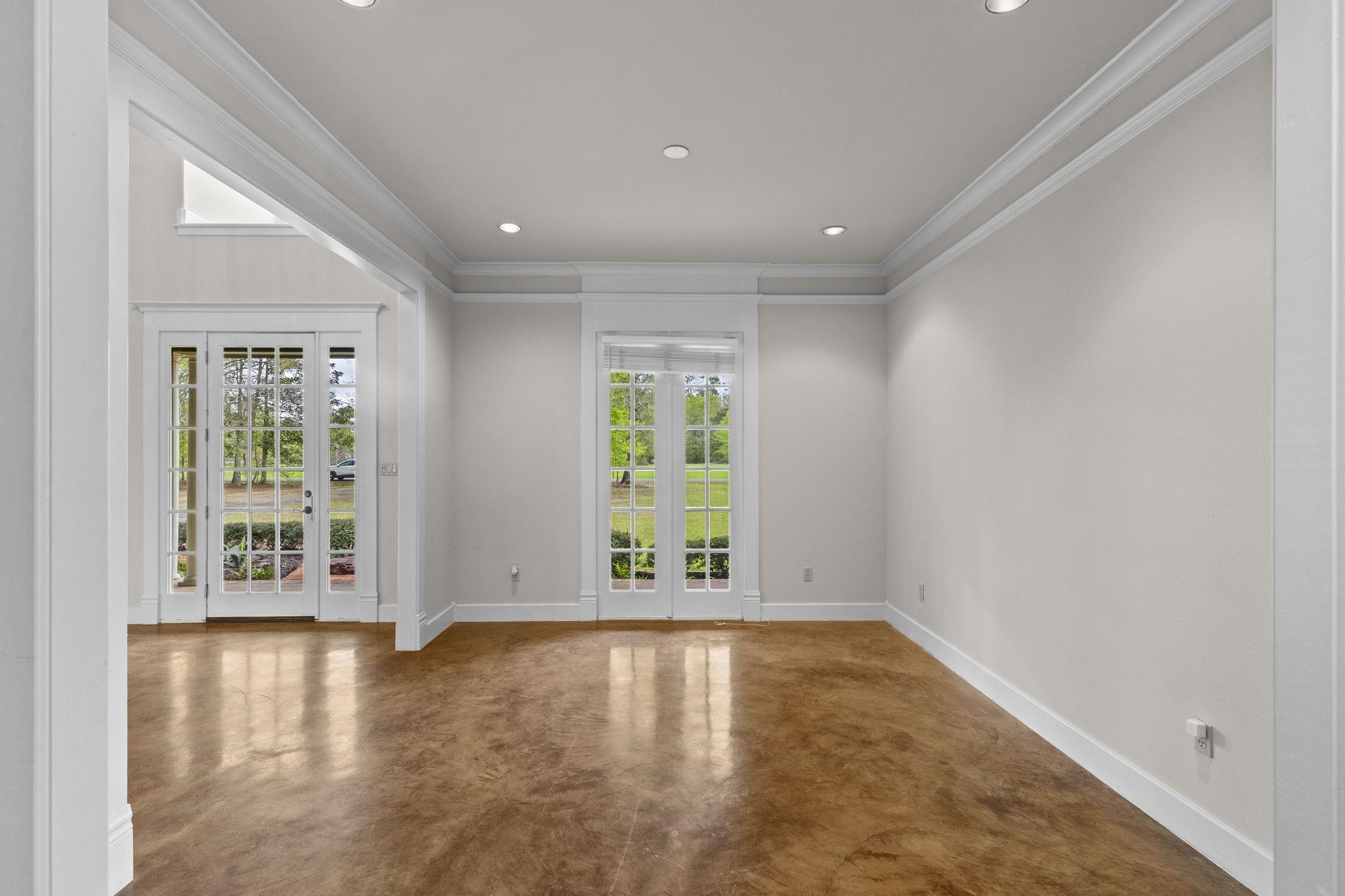 Formal dining or living room with coffered ceiling, French doors to porch, and polished concrete floors