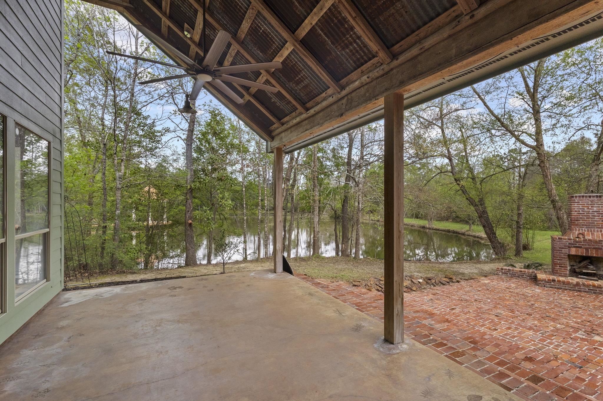 Covered patio with concrete floor and exposed beam ceiling overlooking pond