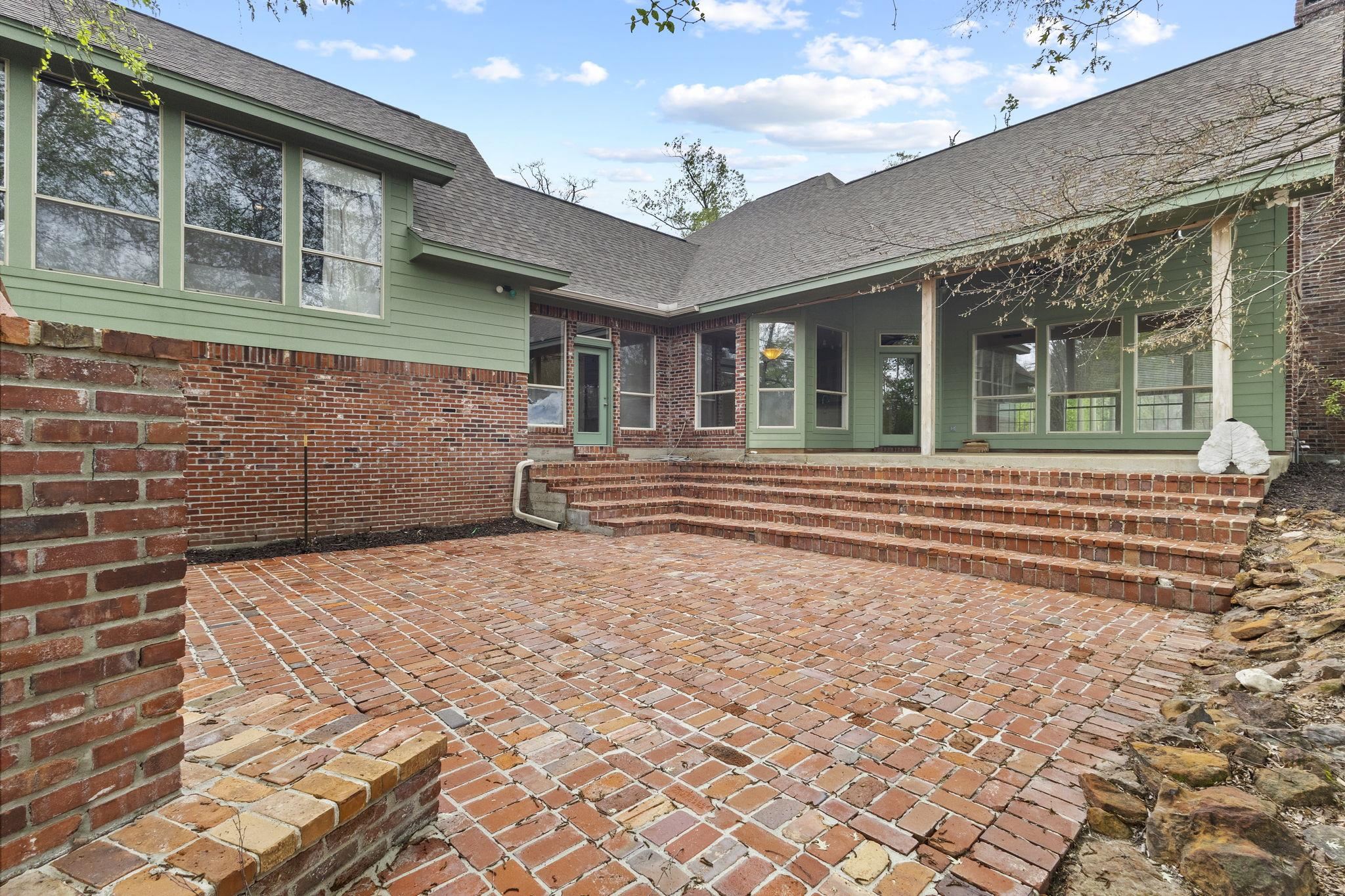 Brick patio with steps and outdoor fireplace near house exterior