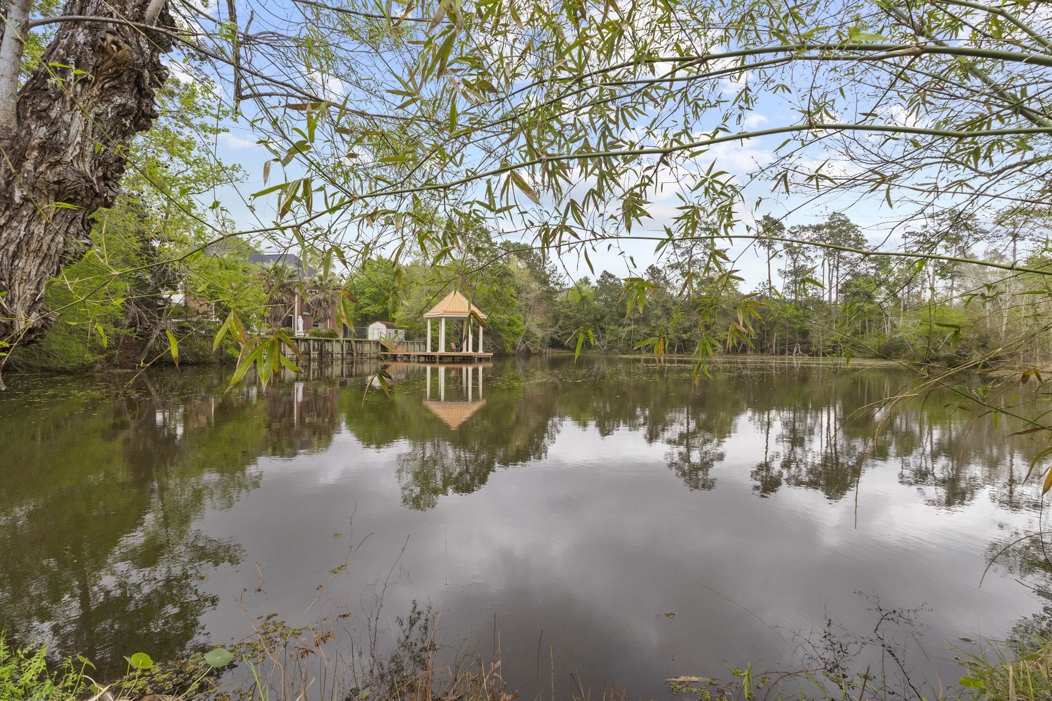 Pond view with gazebo and wooded surroundings reflecting in calm water