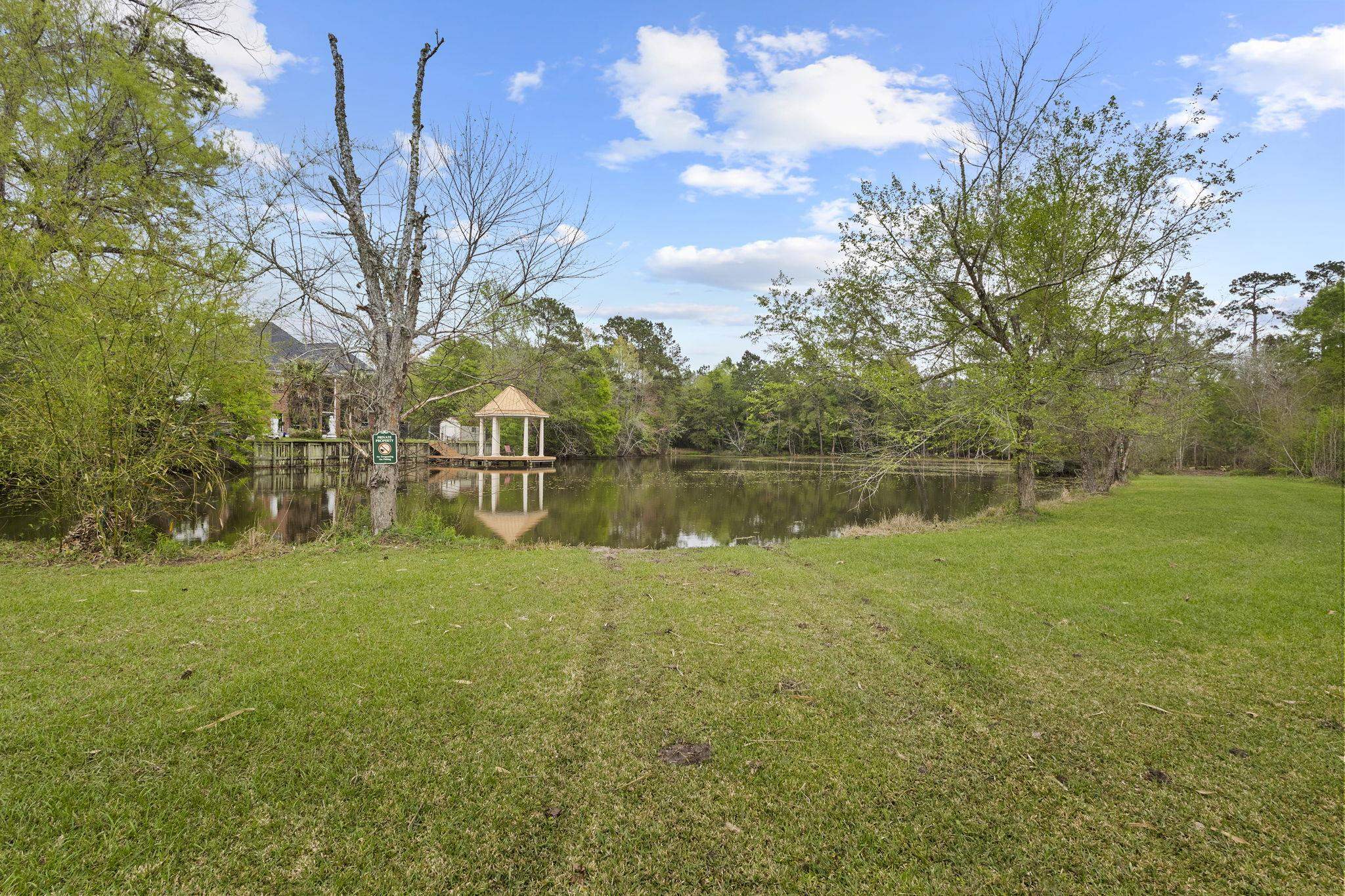 Backyard lawn area with pond and gazebo in wooded natural setting