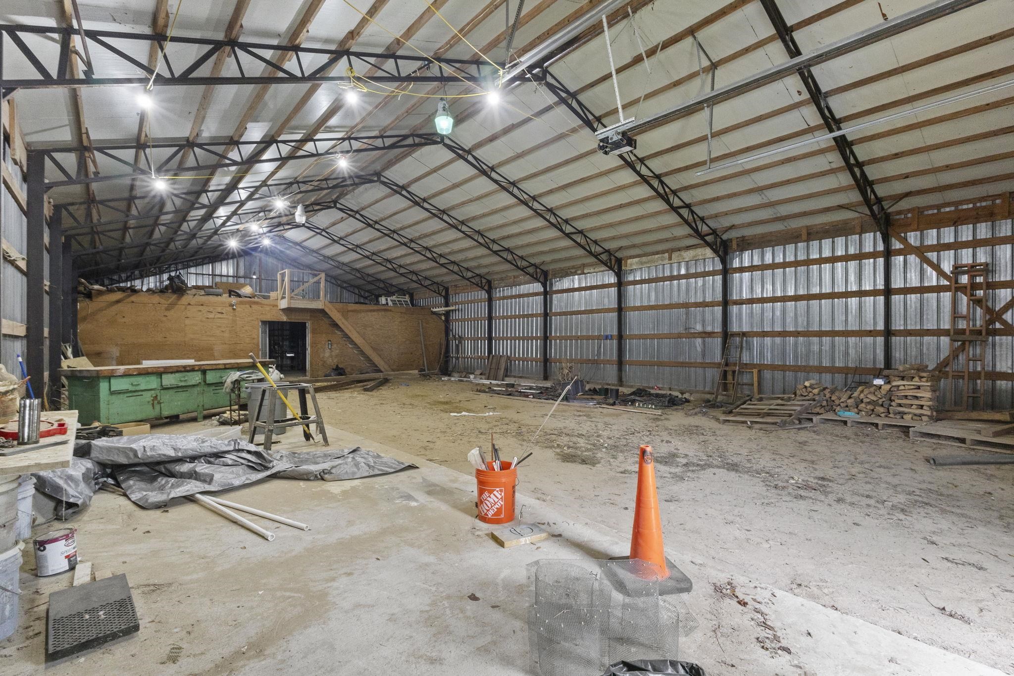 Interior of large metal workshop building with exposed steel framing and construction materials