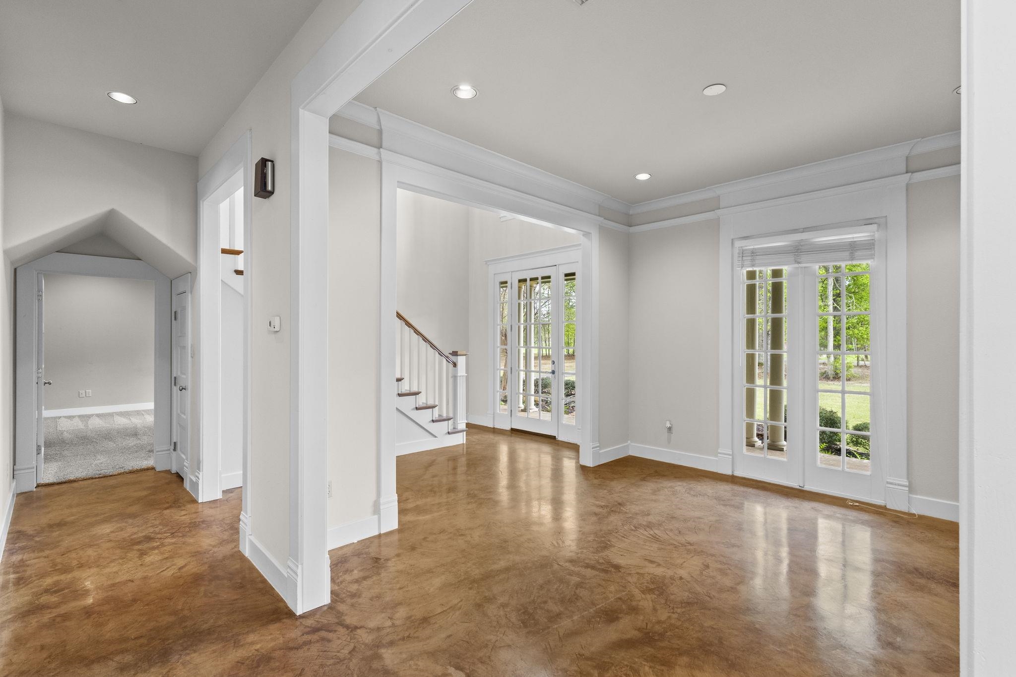 Open concept living area showing connection between rooms with columns, coffered ceiling details, and French door access