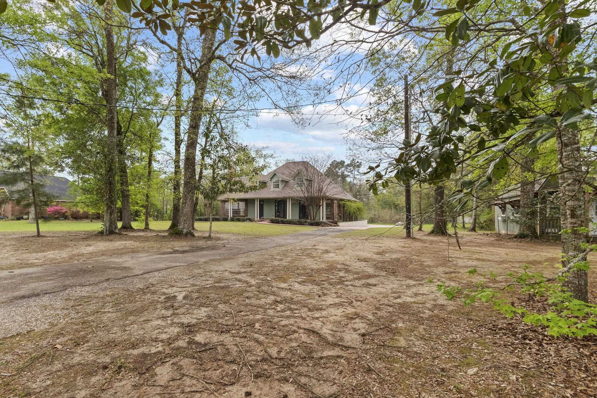 Distant view of the home showing large wooded lot with mature trees and cleared areas around the house