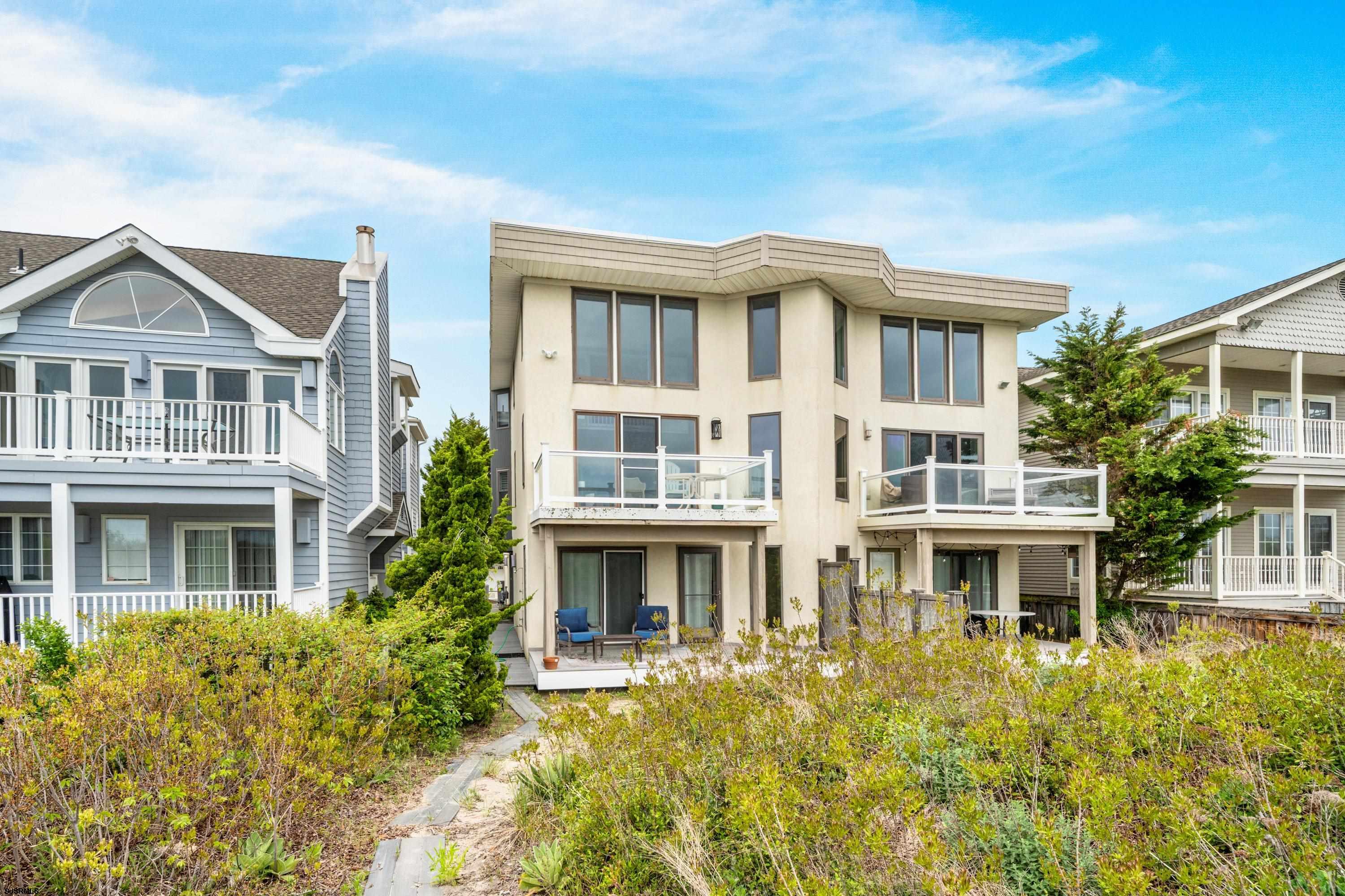 Beautifully updated 4-bedroom, 2.5-bath BEACHFRONT Townhouse offering the perfect blend of coastal comfort and SPECTACULAR VIEWS!  Beach access just steps from your door.  Tucked away in a private setting, this move-in-ready home features spacious living throughout, including a large open living and dining area, soaring high ceilings, and a second family room/den ideal for relaxing or entertaining guests.  The updated kitchen is equipped with stainless steel appliances, granite countertops, and custom wood cabinetry. Enjoy outdoor living at its best with a BEACHFRONT deck, an expansive rear deck and a covered porch on main level with access from 2 bedrooms.  The primary bedroom offers stunning water views, spacious closets and ensuite bathroom, creating a true seaside retreat.  Recent improvements include new paint throughout, new flooring and stylish new furnishings, making this property truly turnkey. Additional features include an attached garage, off-street parking and outside shower. Conveniently located within walking distance to playgrounds, restaurants, shopping, and local attractions.  This townhouse is a great summer getaway or an excellent opportunity for investors seeking a property with a strong rental history. This is a must see.  Easy to show.