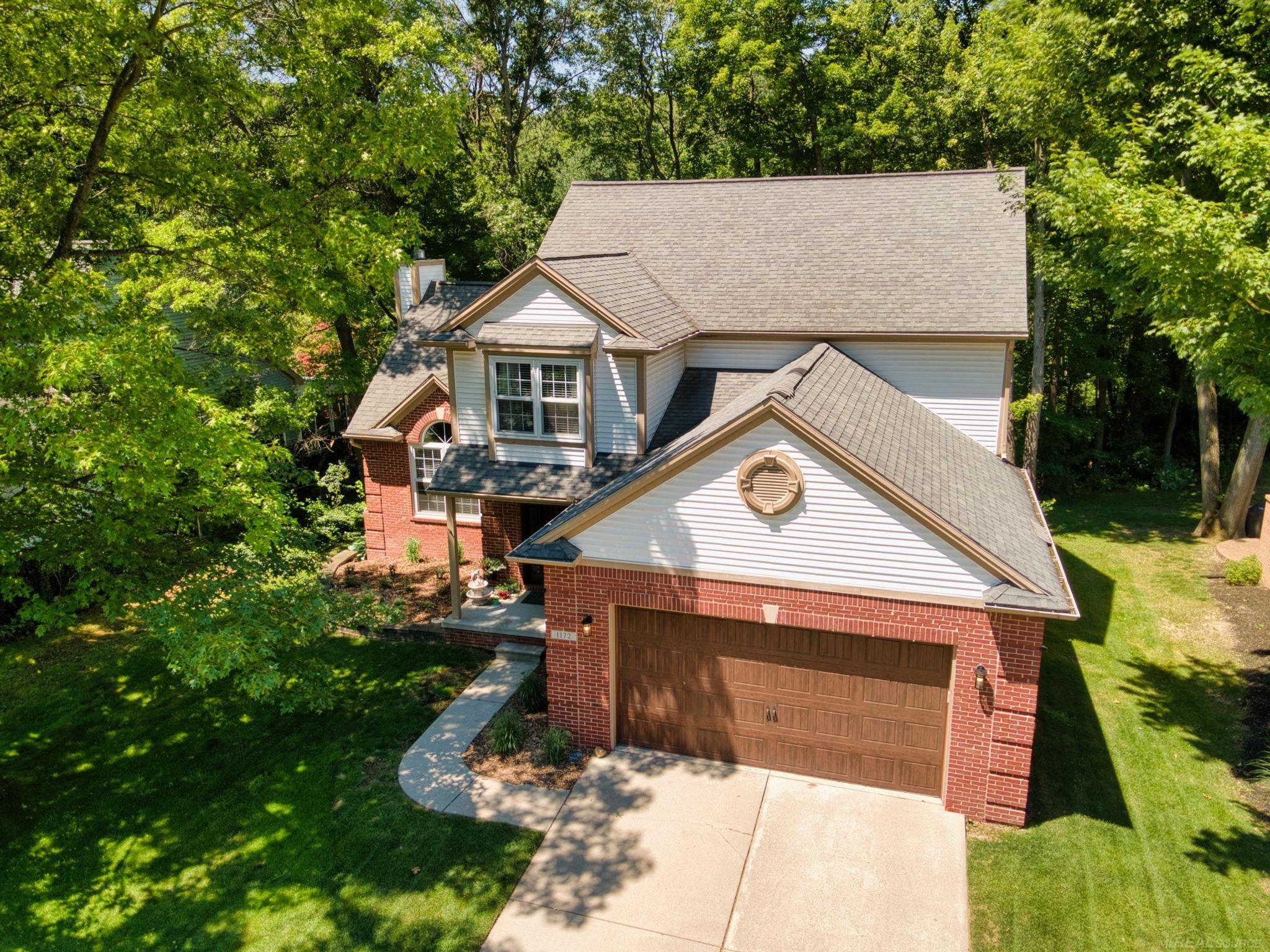 Welcome home to this beautifully maintained colonial nestled in one of Lake Orion's most desirable settings, backing to a peaceful wooded landscape with no neighbors behind! Offering the perfect blend of comfort, privacy, and convenience, this home features an open, functional layout with quality updates throughout.  The main level showcases hardwood flooring throughout most of the first floor, complemented by a dramatic great room with soaring vaulted ceilings and newer Weather Guard windows (approximately 5 years old) that fill the space with natural light. A versatile family room or den with crown molding and a boxed bay window provides the perfect home office, sitting room, or formal living space.  The spacious kitchen is designed for both everyday living and entertaining, featuring a stylish backsplash, newer stainless steel appliances, a center island with solid surface countertops, a pantry for added storage and a large breakfast nook. Just off the kitchen, the large first-floor laundry room includes a utility sink, built-in shelving, and a convenient drop station to help keep everything organized. A powder room completes the main level.  Upstairs, the spacious primary suite offers a cathedral ceiling, ceiling fan, and a private en-suite bath with dual sinks, a jetted soaking tub, and separate stall shower. 3 other spacious bedrooms give plenty of room for comfortable and functional living. The full family bath offers dual sinks and a tub/shower combination.  Step outside onto the wood deck and enjoy the tranquility of the private backyard, surrounded by mature trees and natural landscaping. Additional highlights include an unfinished daylight basement plumbed for a future bathroom, providing endless possibilities for additional living space, as well as an insulated garage door, lawn sprinkler system, home security alarm, and a humidifier on the furnace.  Major mechanical updates include a furnace and hot water heater replaced within the last five years, providing added peace of mind.  Ideally located near