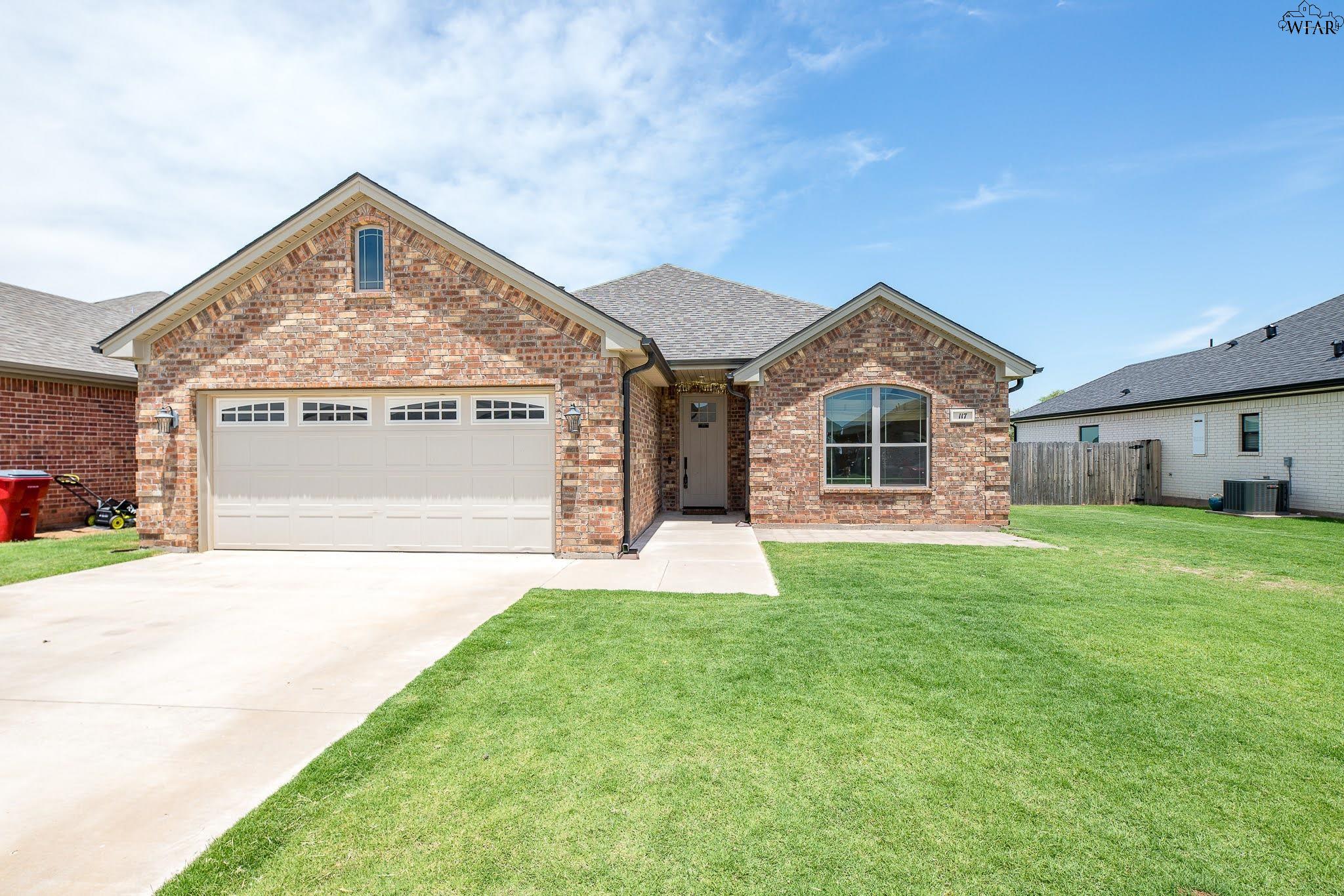Brick house with a two-car garage, covered entry, and broad front lawn.