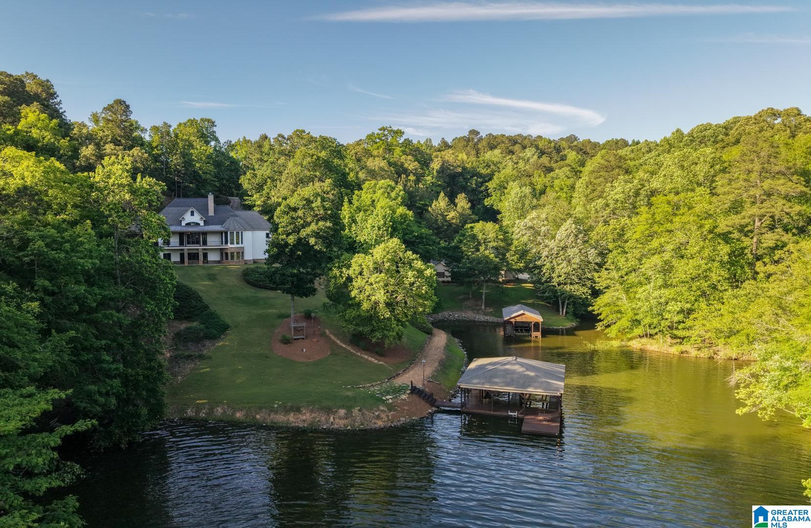 Stag Cove is tucked into a private, protected cove on Neely Henry Lake. This 8.1-acre estate offers a rare blend of serenity, privacy, and adventure. The centerpiece is 650+ feet of shoreline with deep, calm water, featuring two covered docks with three slips. The home and boathouse maximize these views through a screened porch, covered deck, and patio, perfect for everything from slow mornings to full-house weekends. The interior shines with refinished hardwoods, granite countertops, cathedral ceilings, and a main-level primary suite. With two parcels and no HOA, you have total freedom. Beyond the main acreage, 5 +/- additional peninsula acres are available for even more control of your surroundings. Functional amenities include a 2,500 sq. ft. detached workshop/guest suite and 30’ x 40’ RV/boat storage. Located 19 miles from Gadsden and 60 miles from Birmingham, this is a turnkey waterfront retreat. Full property tours and spec sheets at locklearliving.com - featured properties.