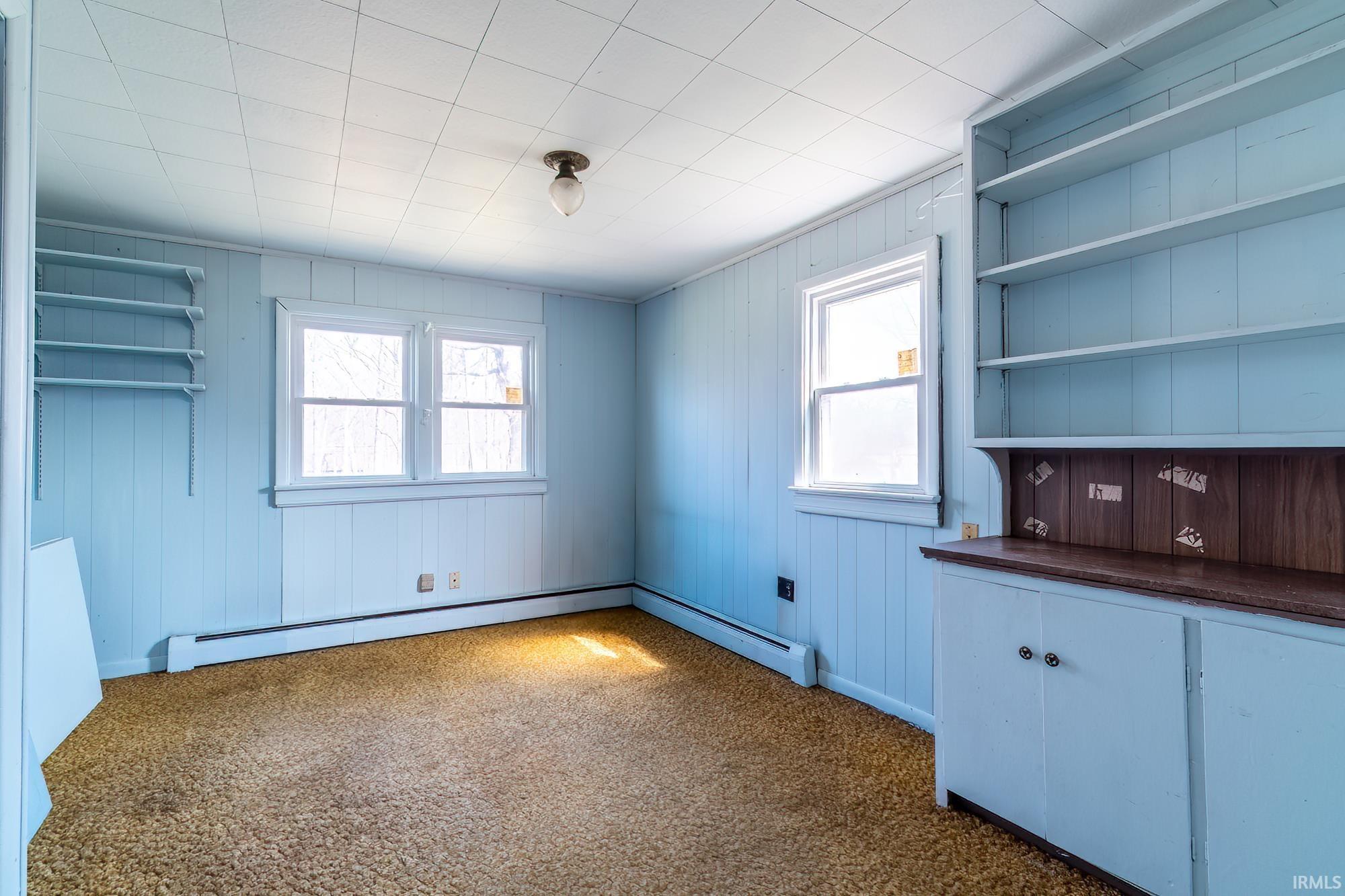 Unfurnished dining area featuring a baseboard heating unit and dark carpet