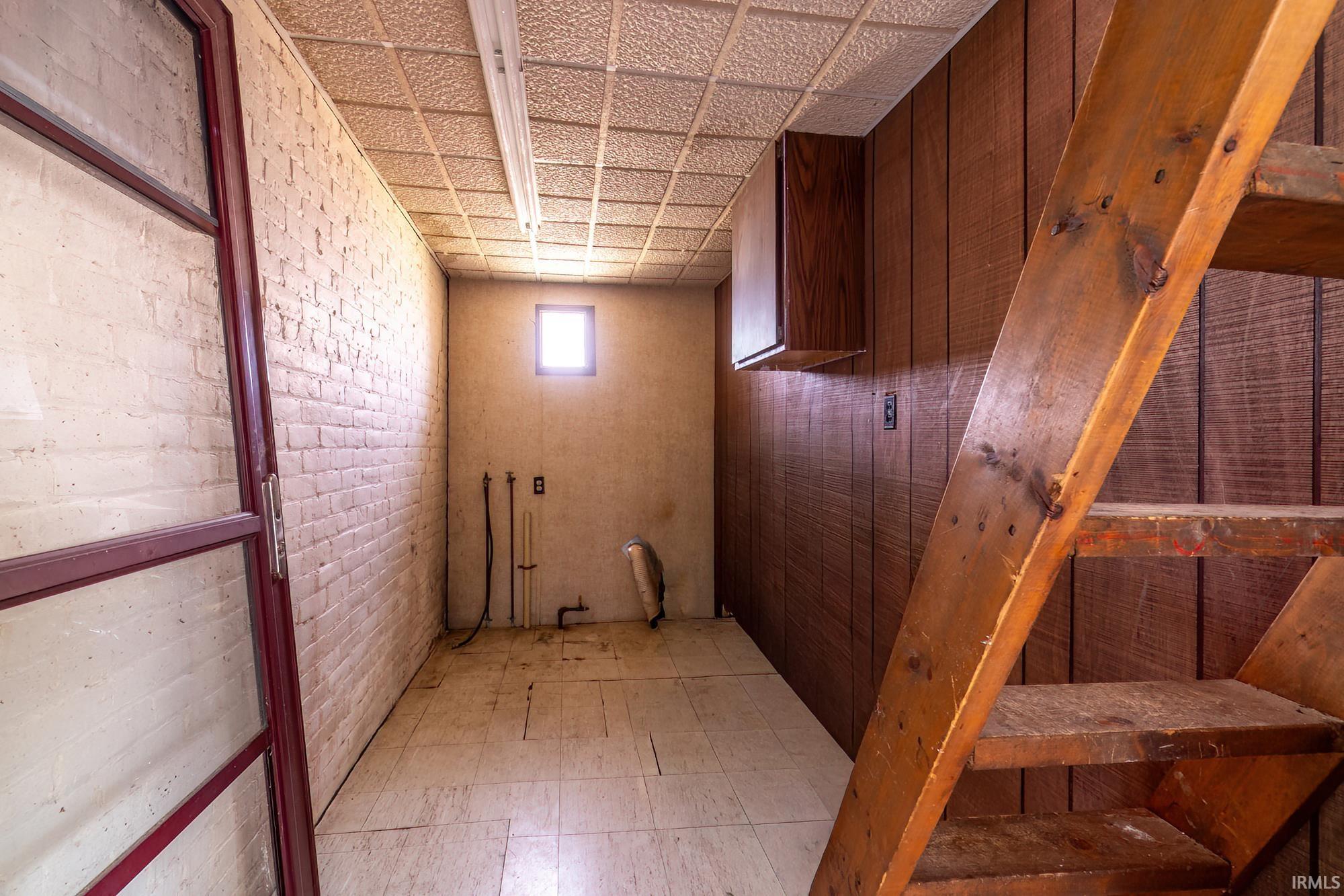 Laundry area featuring light floors and brick wall