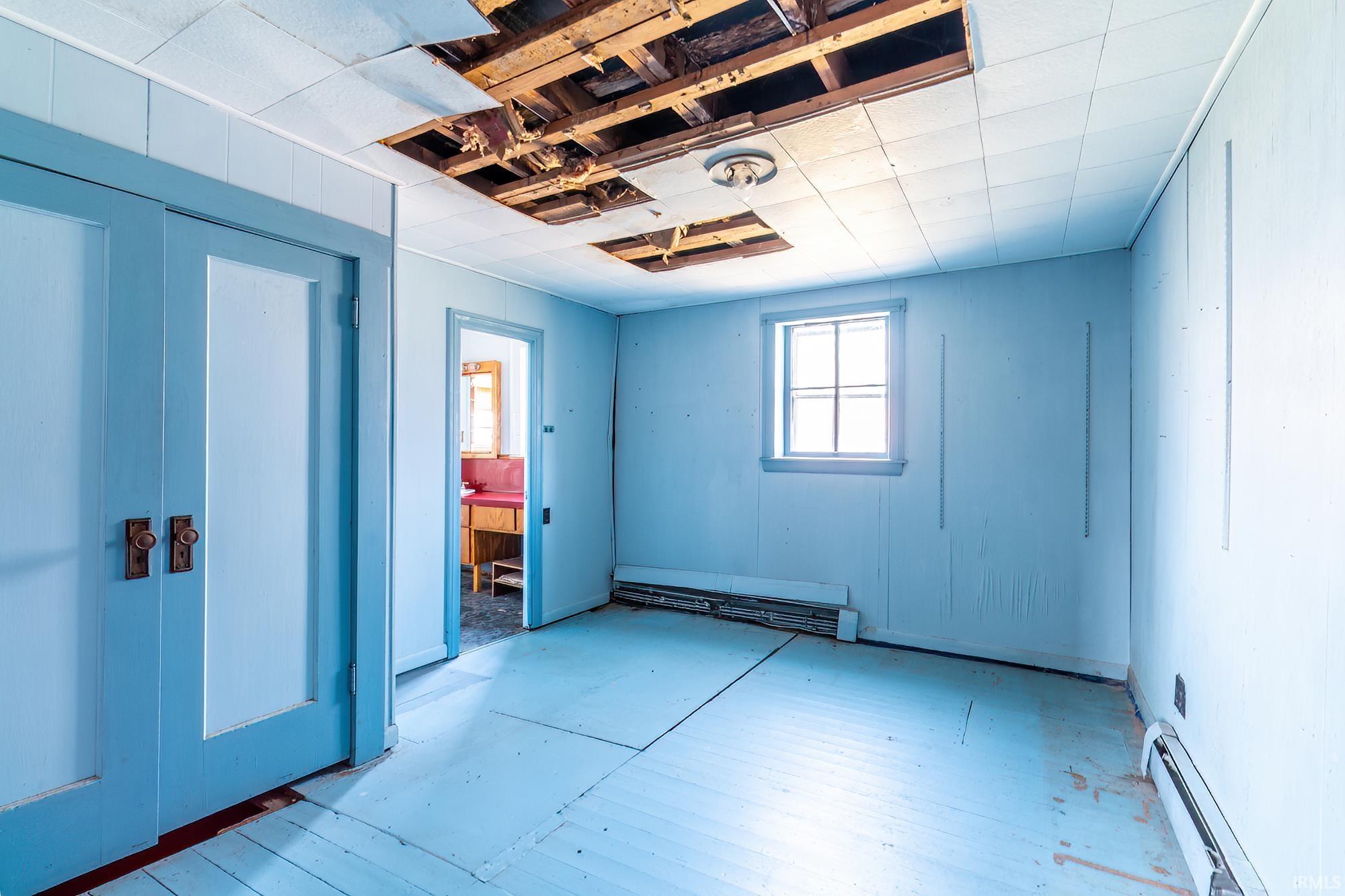Unfurnished bedroom featuring a baseboard radiator and a closet