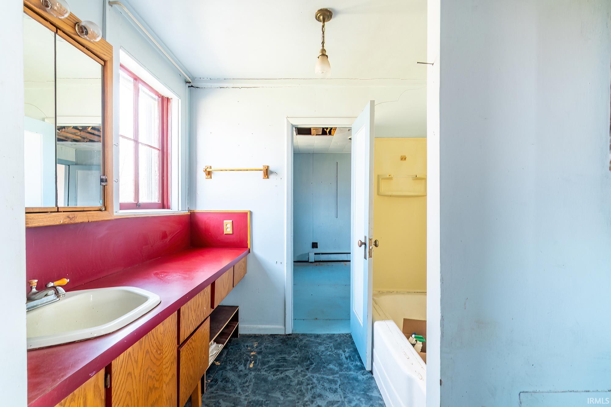 Bathroom featuring a garden tub, vanity, and baseboard heating