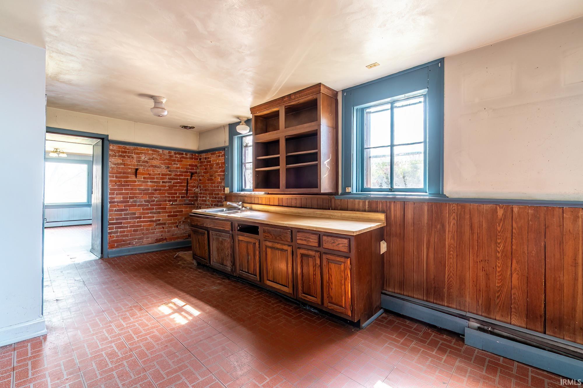 Bar area featuring light countertops, a baseboard heating unit, open shelves, and brick patterned flooring