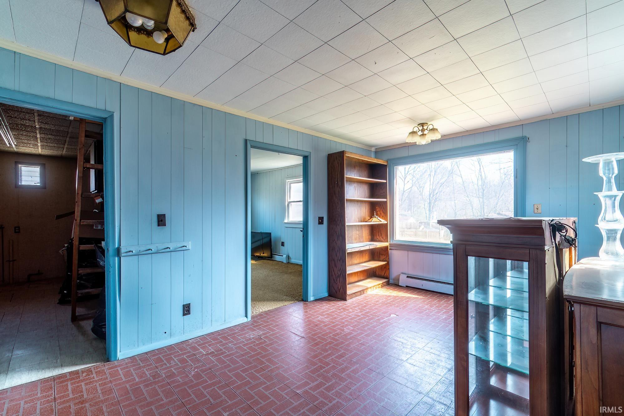 Dining area featuring wooden walls, brick patterned floors, and a baseboard heating unit