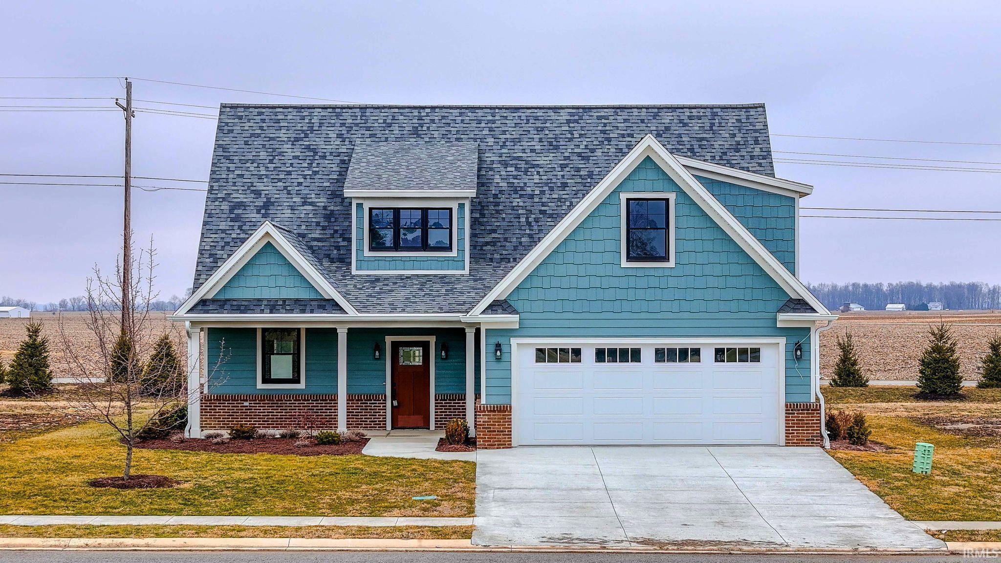 View of front facade with a porch, roof with shingles, a front yard, concrete driveway, and brick siding