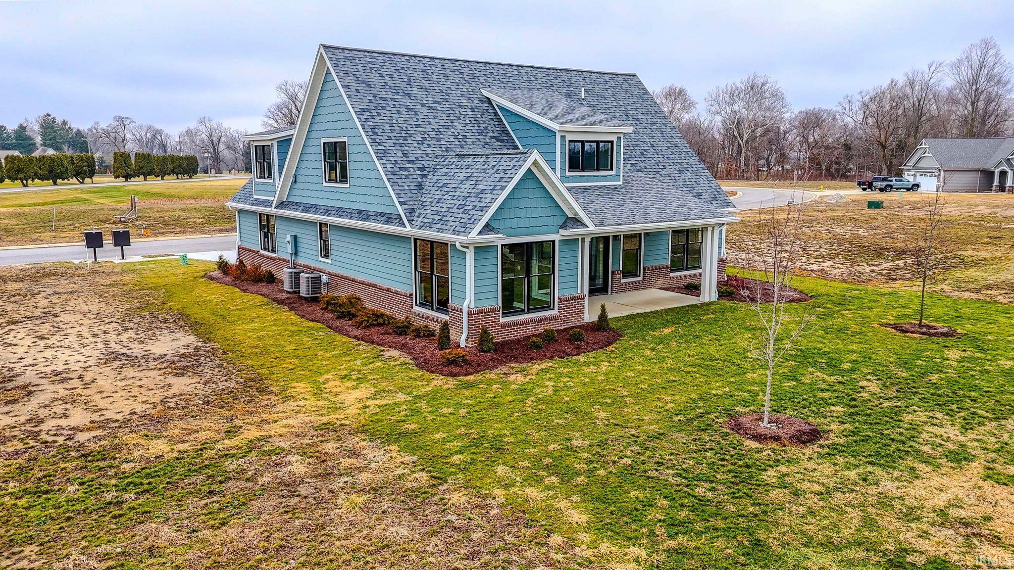 View of front of home featuring brick siding, roof with shingles, a front lawn, and a sunroom