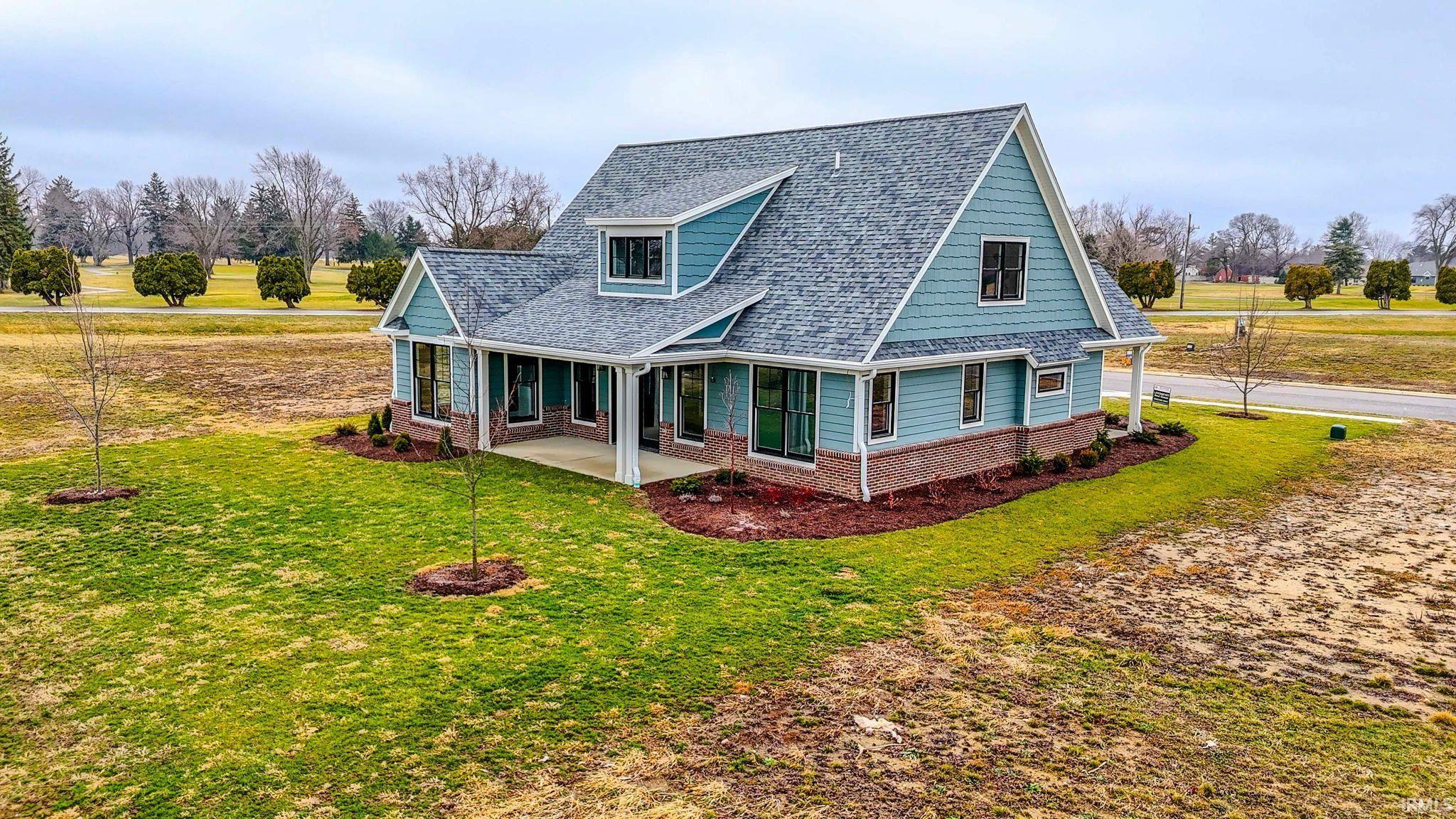 Rear view of house with brick siding, a shingled roof, and a lawn