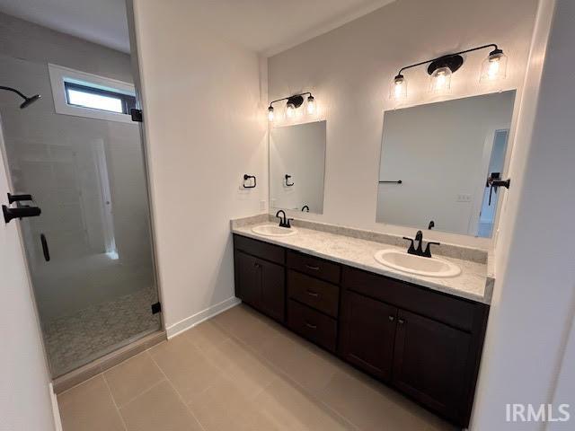 Bathroom with double vanity, a stall shower, and light tile patterned floors