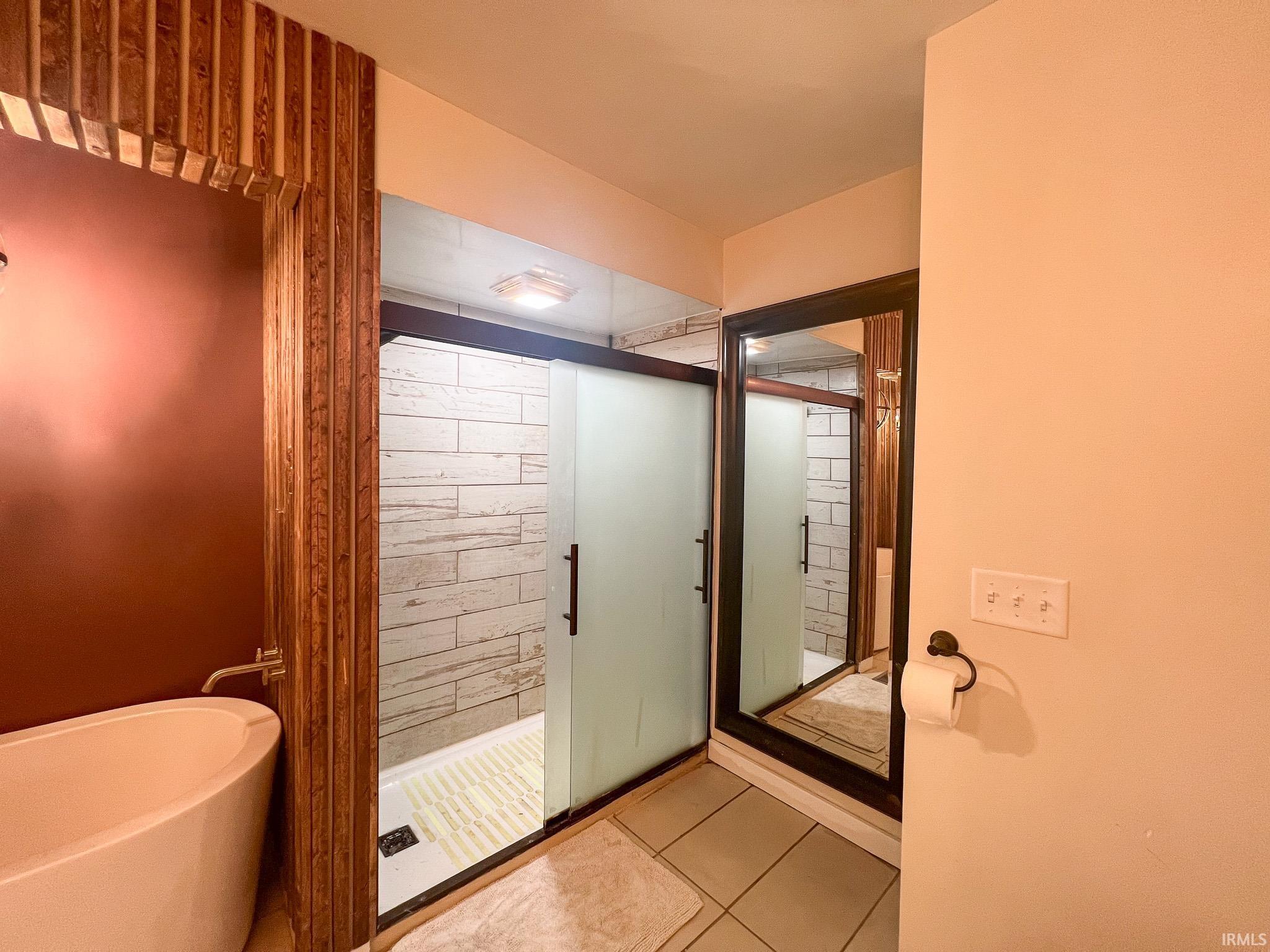 Bathroom with a stall shower, a freestanding tub, and tile patterned floors