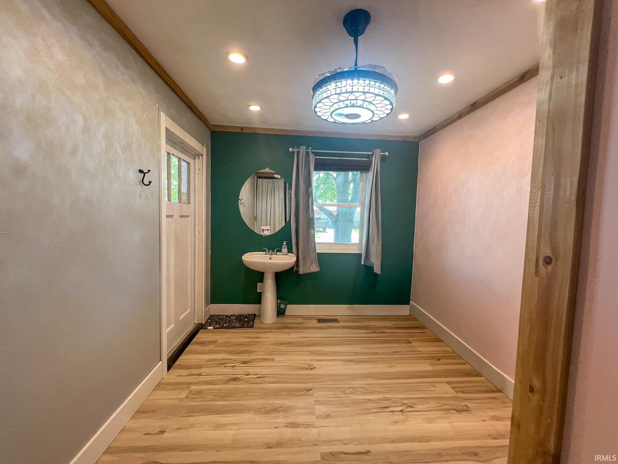 Bedroom 3 converted into an in-home salon with light wood-style flooring, ornamental molding, and recessed lighting