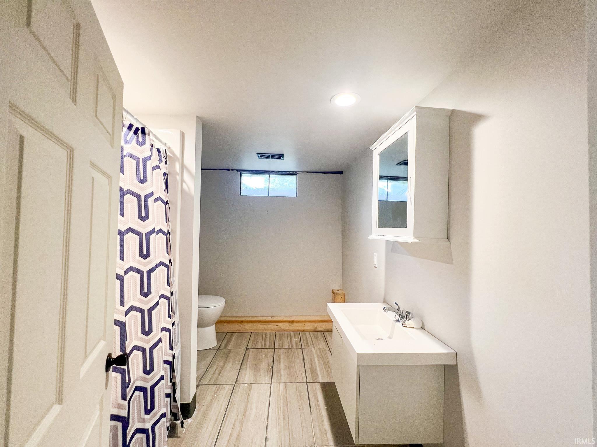 Full bath in basement featuring vanity, curtained shower, and recessed lighting