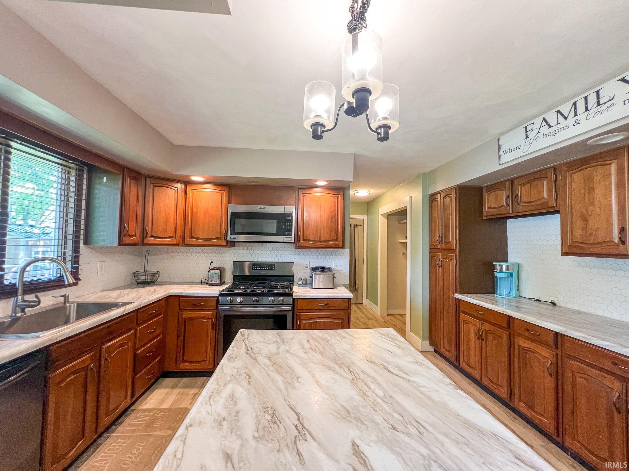 Kitchen featuring plenty of cabinets, tasteful backsplash, appliances with stainless steel finishes, and light wood-style flooring