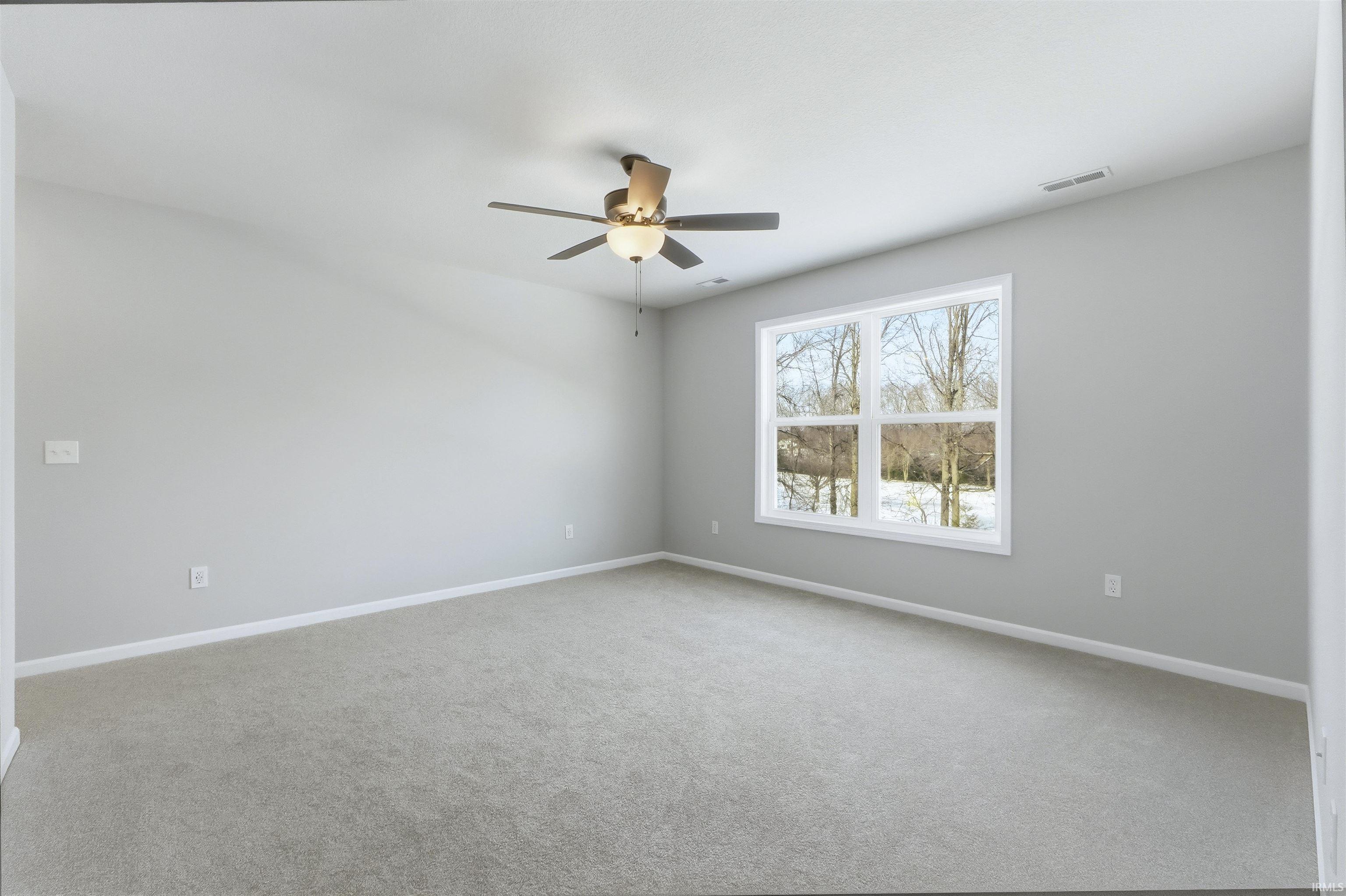 Carpeted spare room featuring baseboards and ceiling fan