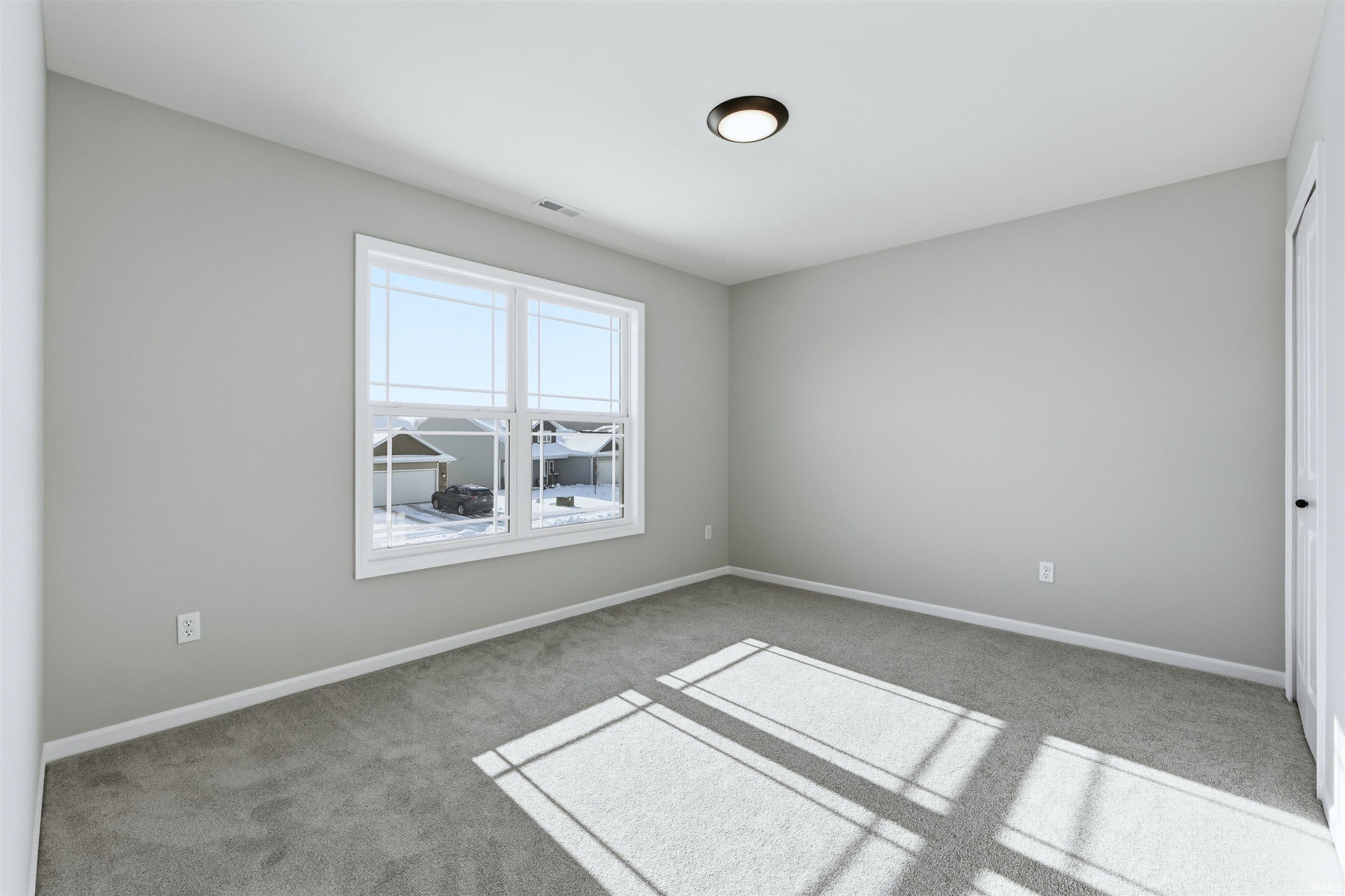 Spare room featuring light carpet and baseboards