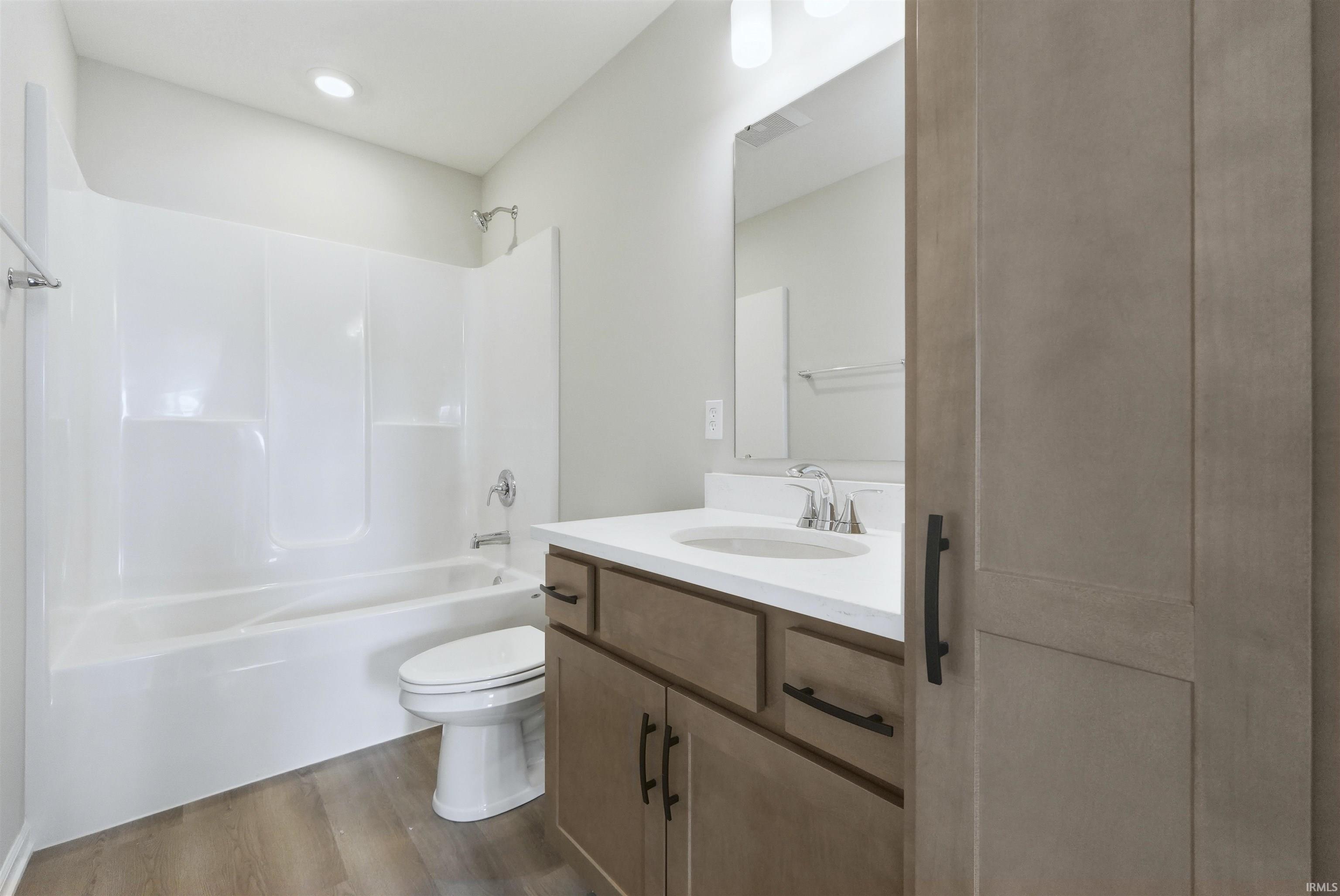 Bathroom featuring vanity, dark wood-type flooring, and shower / bathtub combination